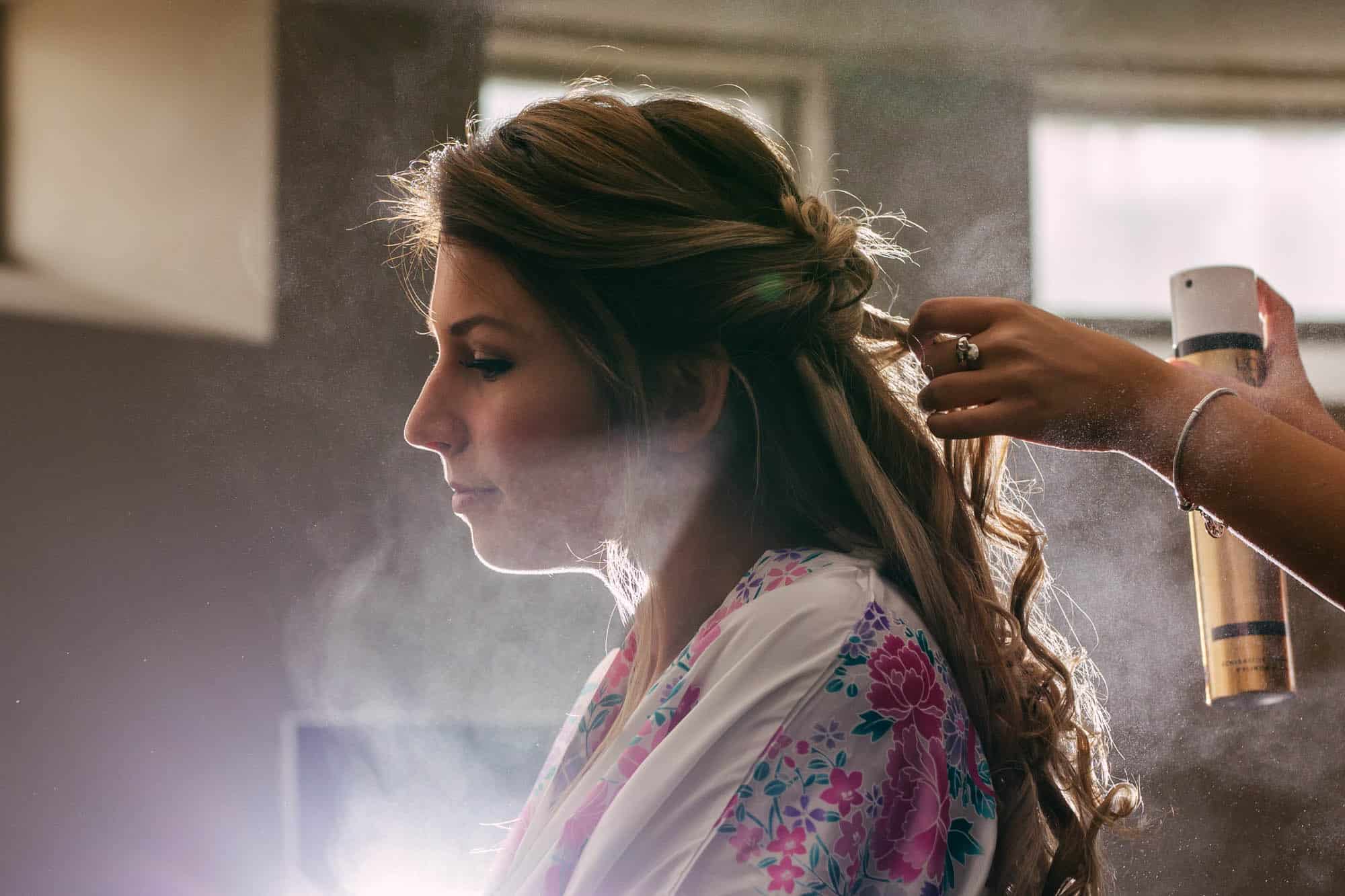 A woman starting to plan her wedding while having her hair done in front of the mirror.