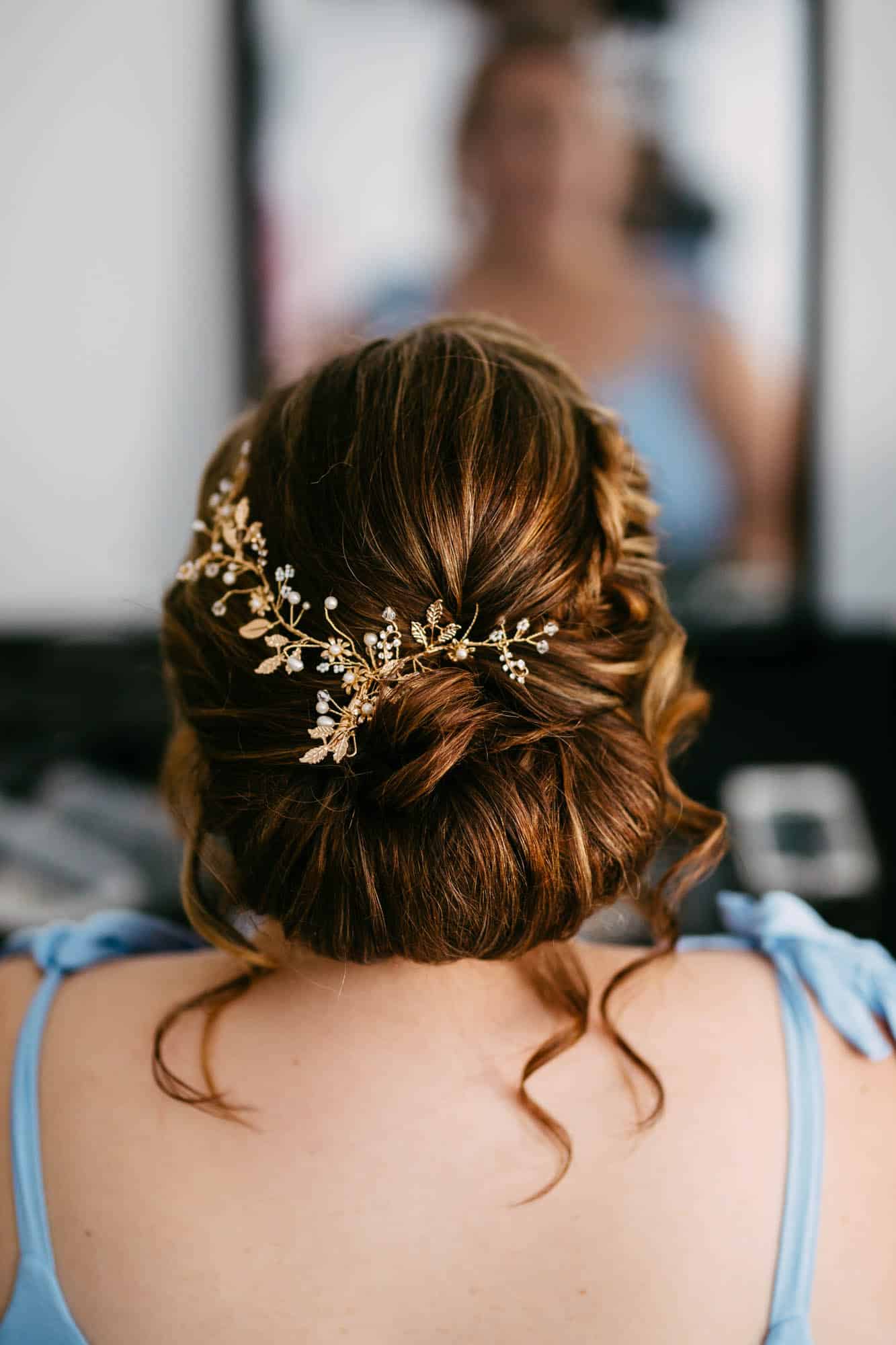     Beschrijving: De achterkant van het haar van een bruid, versierd met een gouden bloemhoofddeksel in haar bruidskapsels.
