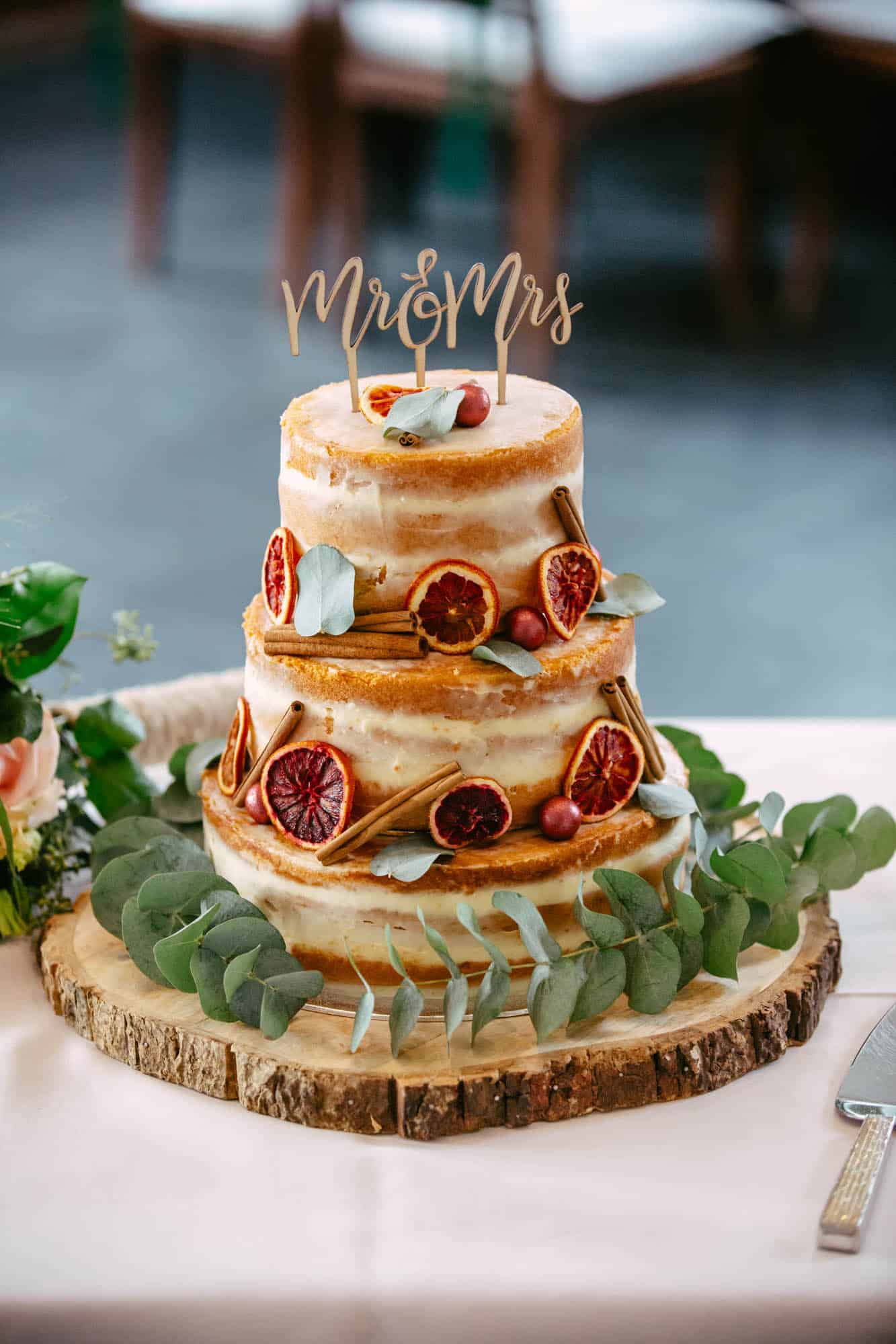 A three-tier wedding cake with a wooden Mr. and Mrs. cake topper.