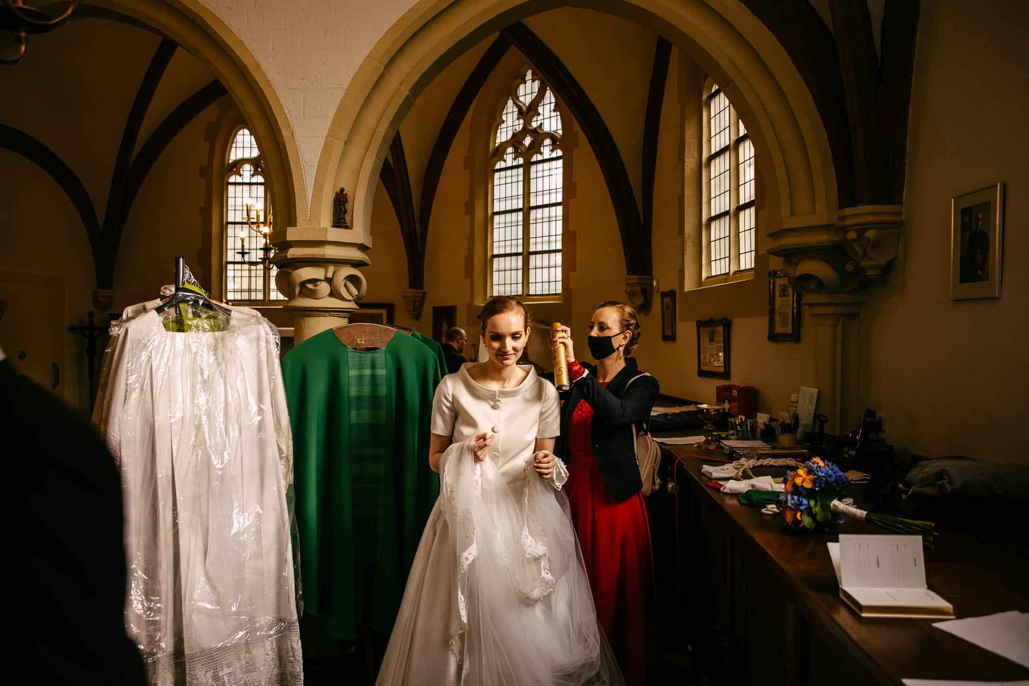 De ceremoniemeester helpt de bruid met het klaarmaken in een kerk.