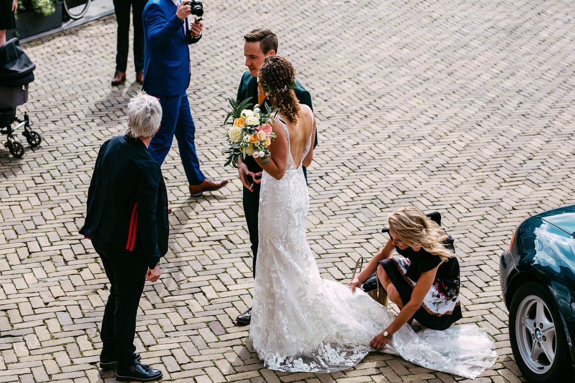 Ceremoniemeester helpt bruid met de trouwjurk