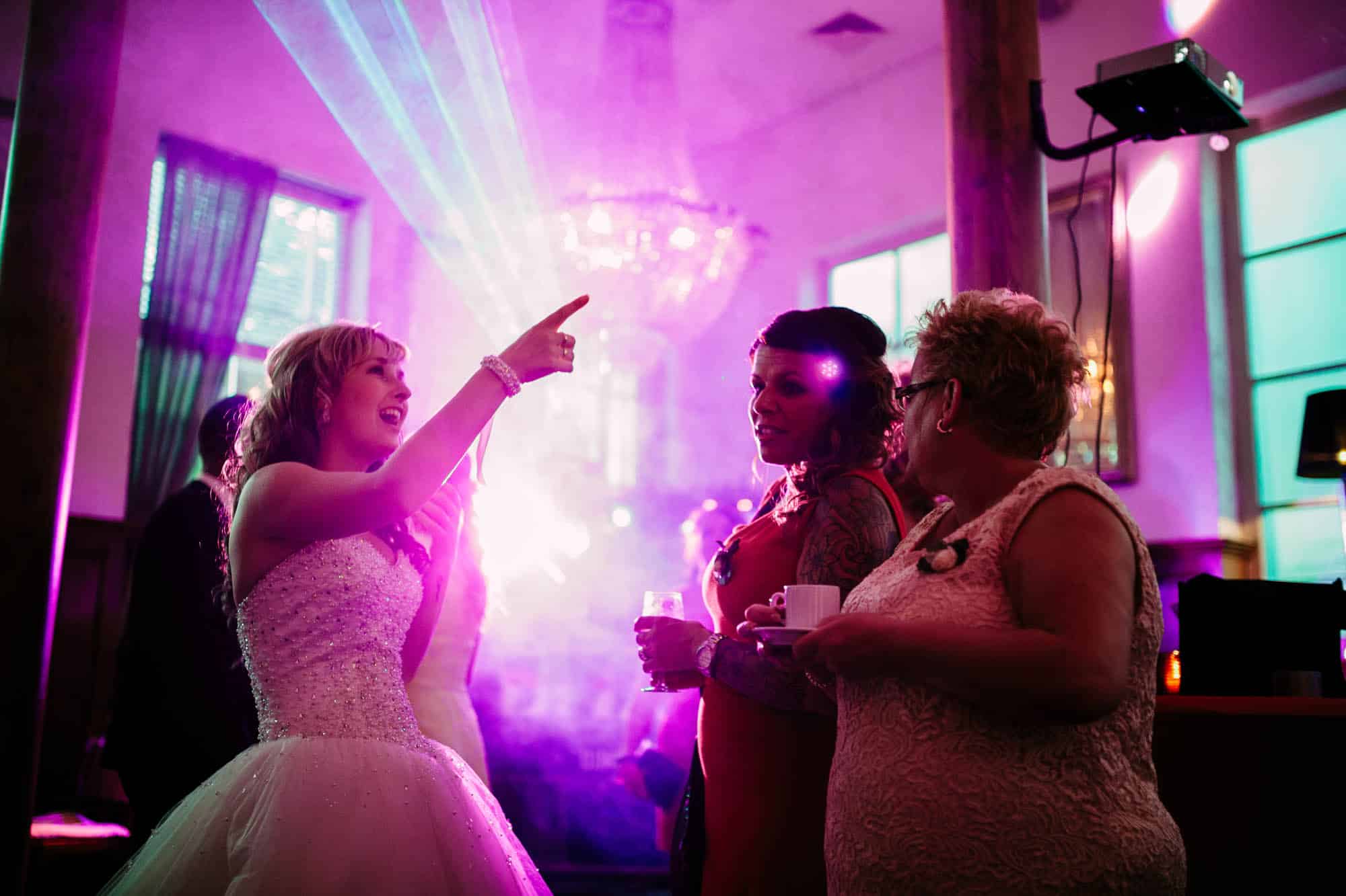 Een vrouw in een trouwjurk wijzend naar een paars licht.