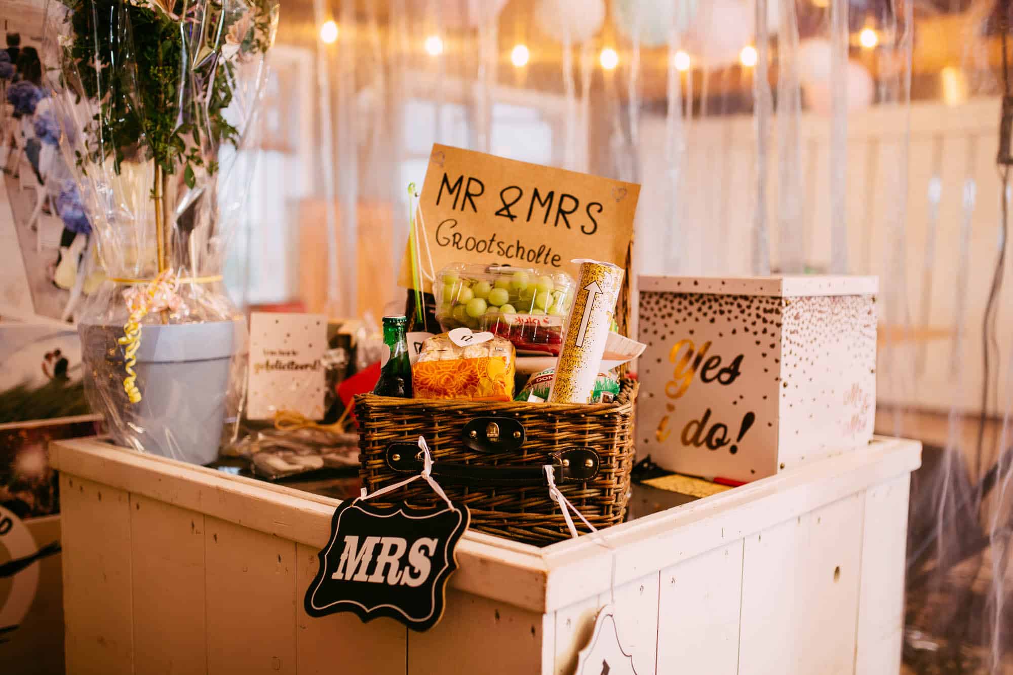 A wedding day gift: A table with a basket of Mr and Mrs plates and balloons.