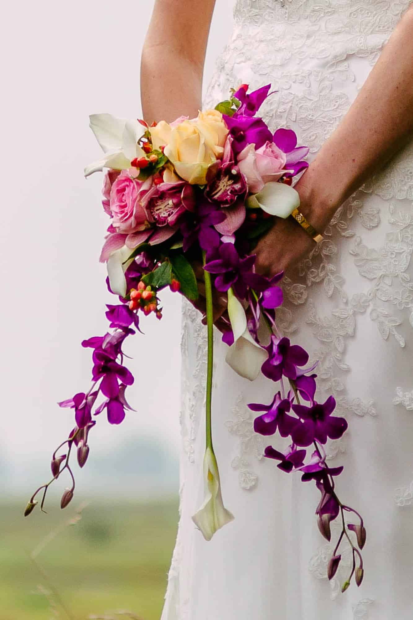 A bride loves a wedding bouquet of orchids and purple flowers large.