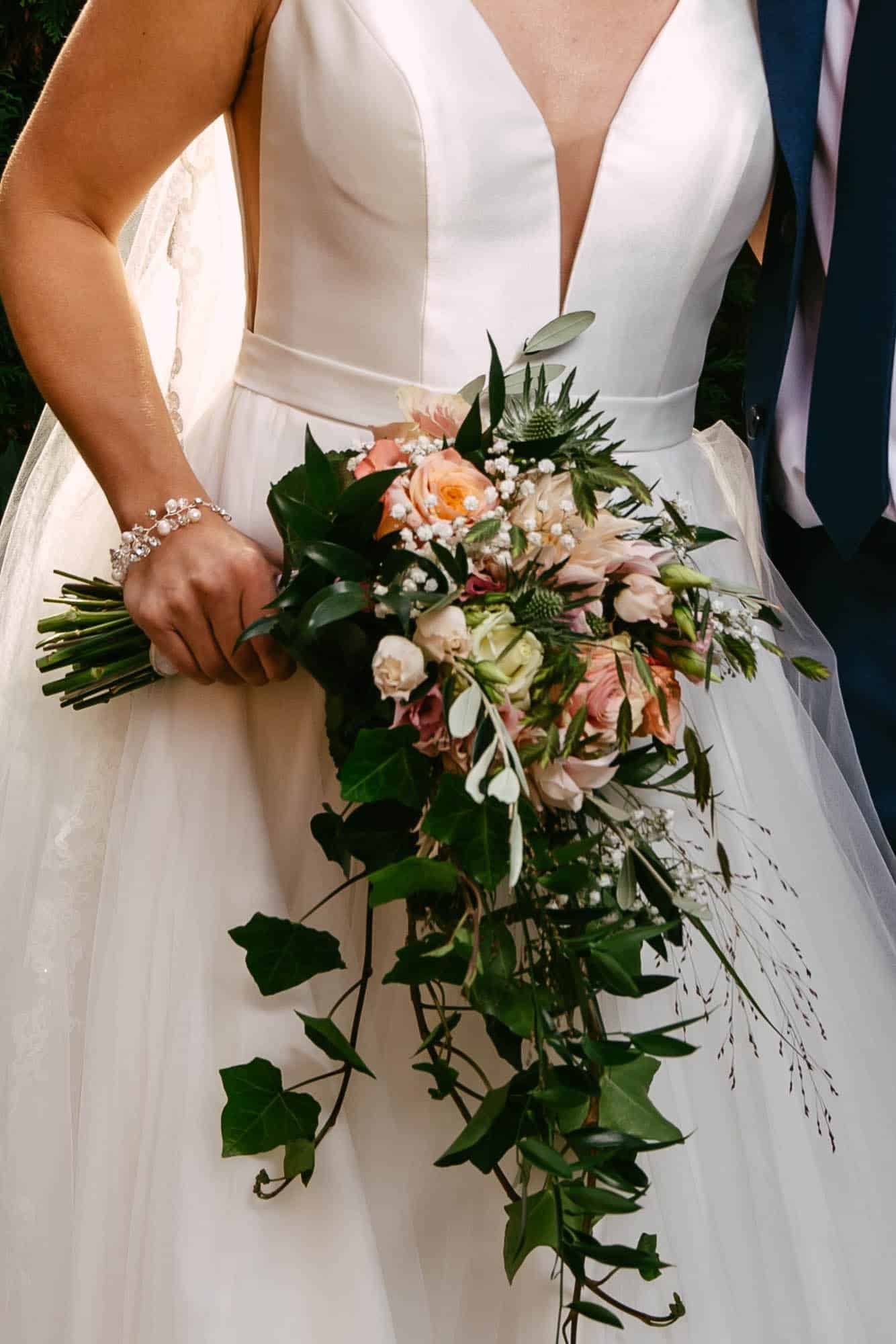 A bride and groom hold a wedding bouquet.