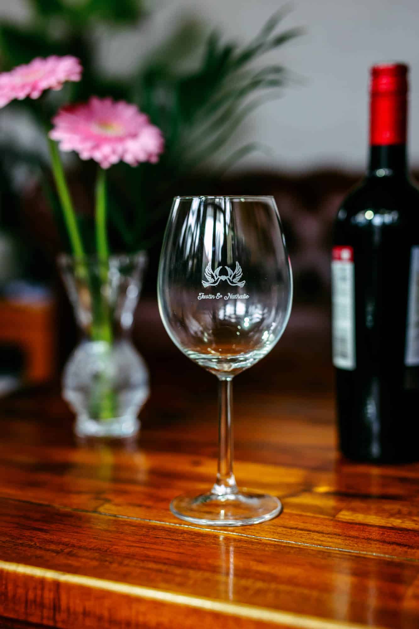 Een wijnglas op tafel naast een fles wijn, het perfecte trouwdagcadeau.