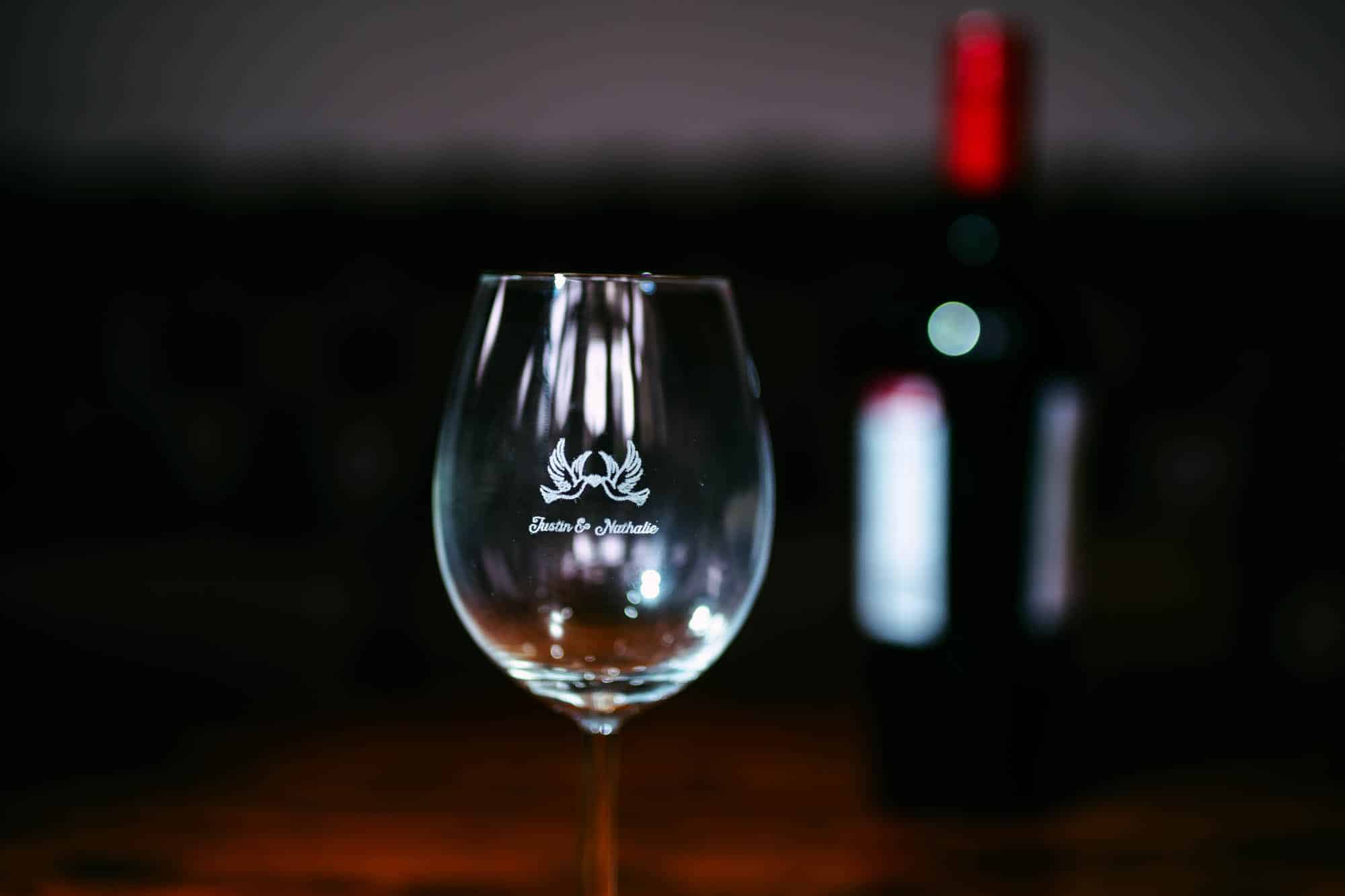 Een wijnglas, een mooi trouwdagcadeau, zittend op een tafel naast een fles wijn.