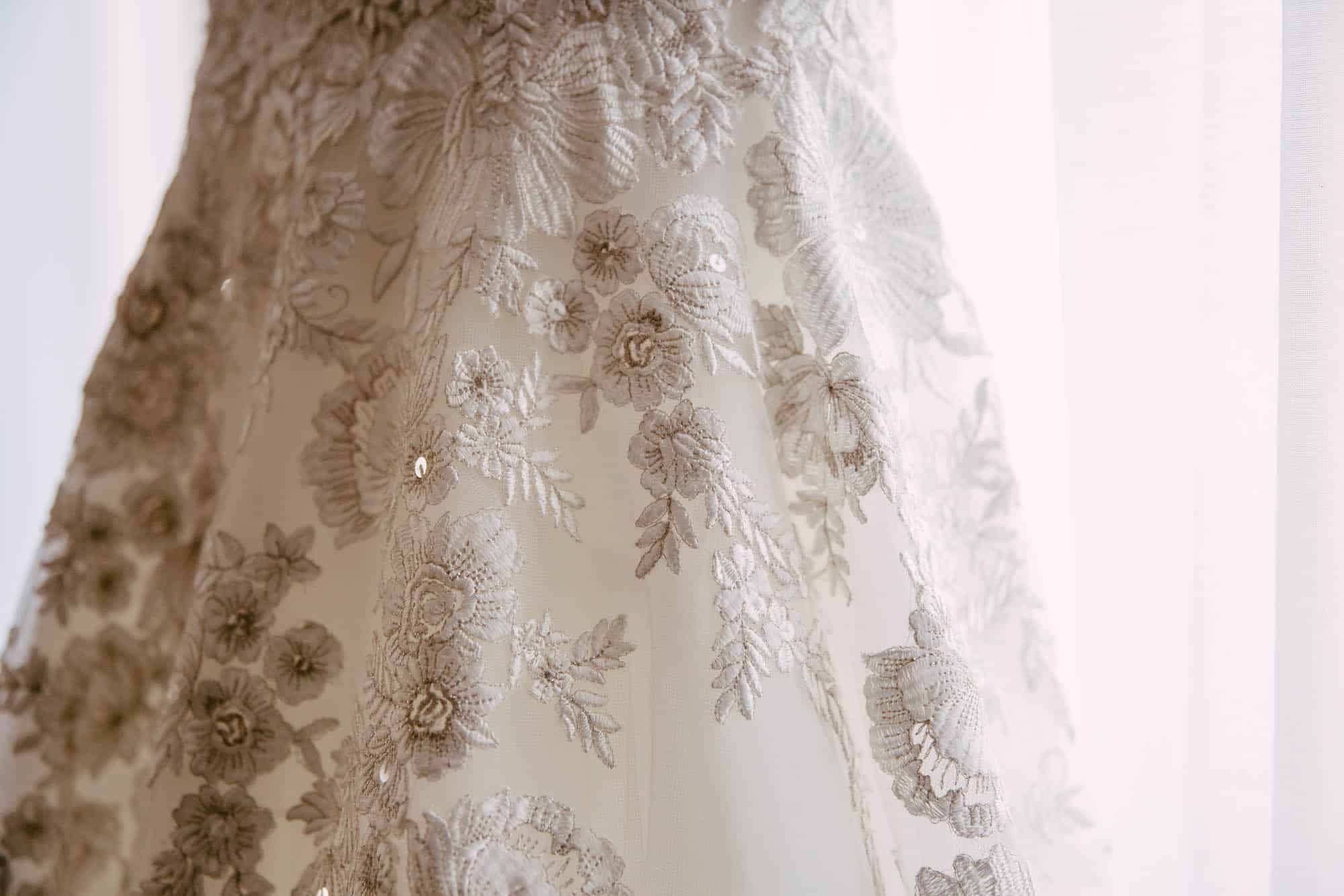        A line of wedding dress hangs on a windowsill.