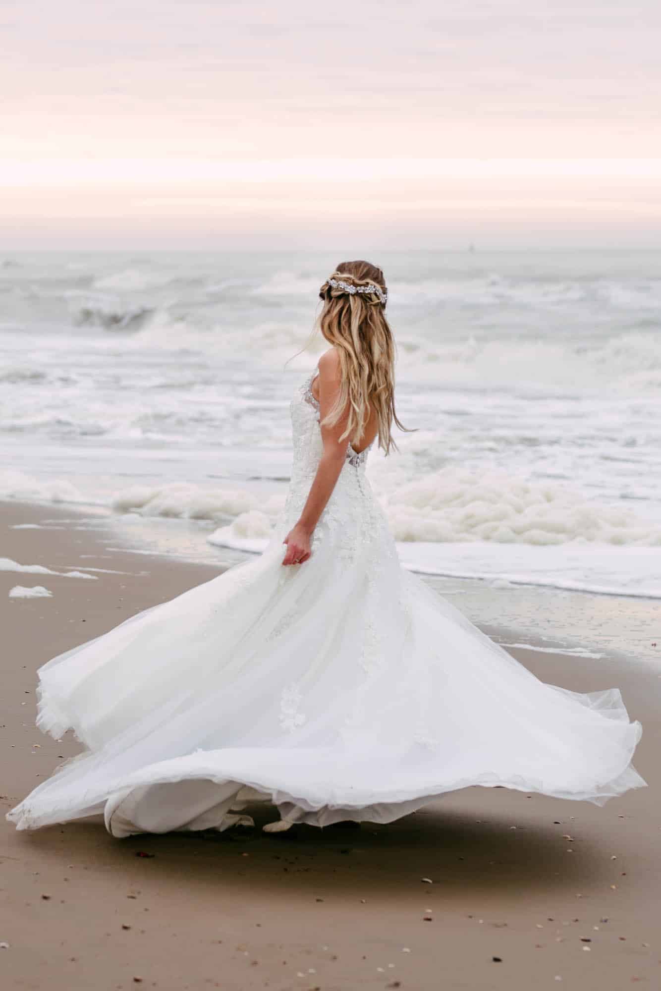 A bride in an A-line wedding dress walking along the beach.