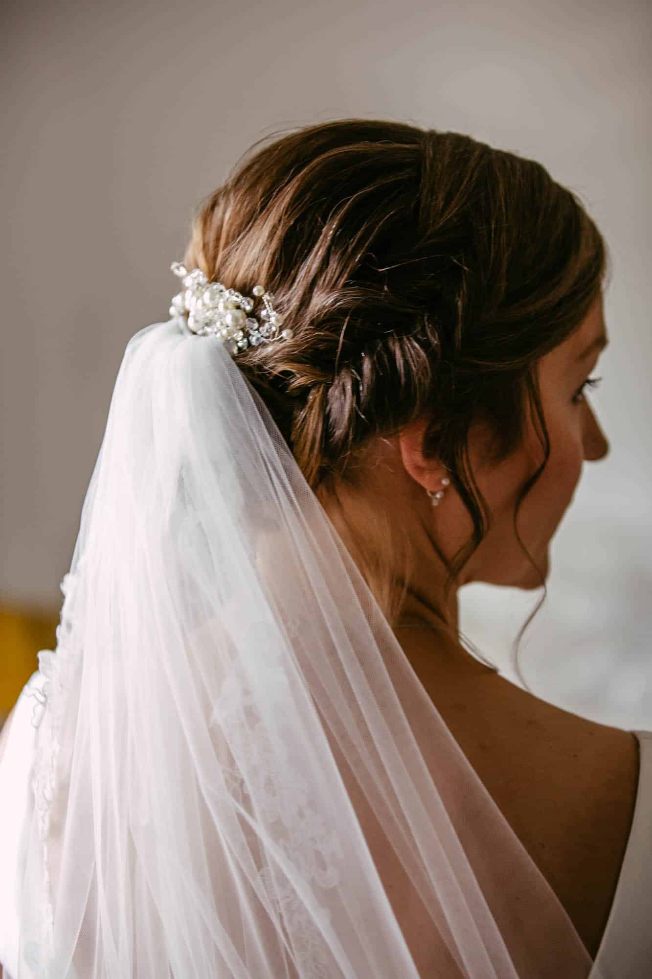 Een bruid met een sluier in het haar, met prachtige bruidskapsels.