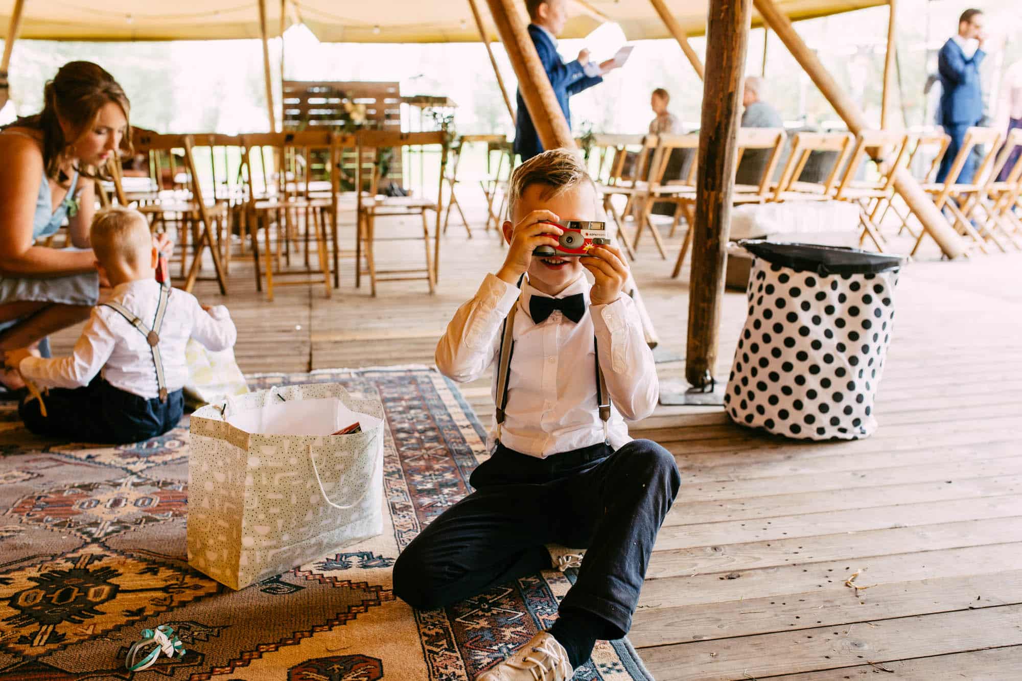 Een jongetje zit op de grond voor een tent, verdiept in bruiloftsspelletjes.