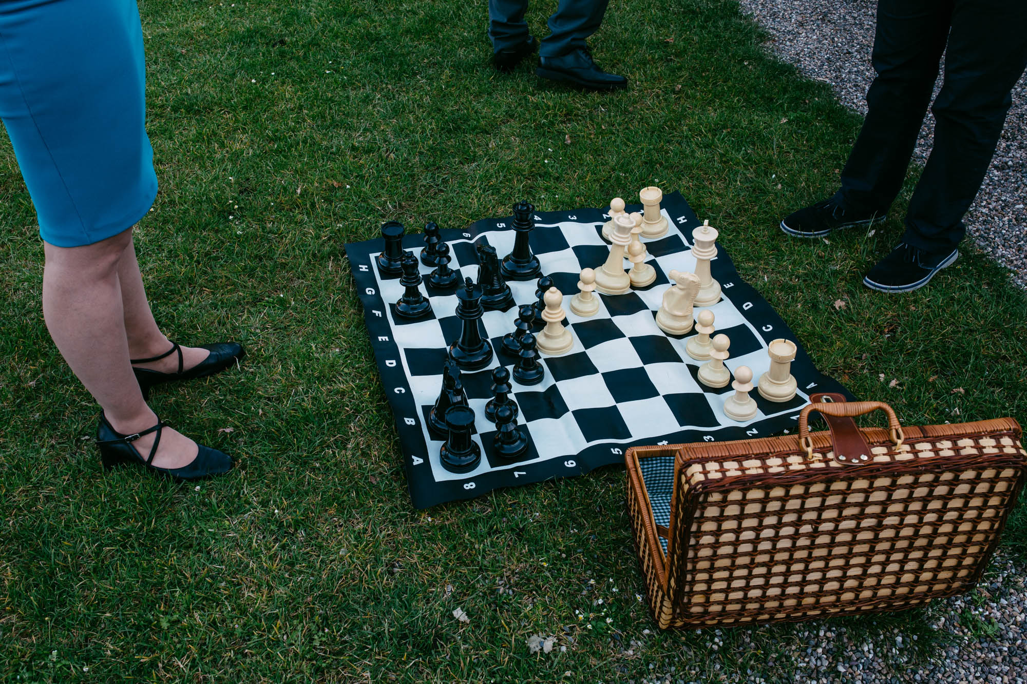 A group of people play chess on the grass during a wedding.