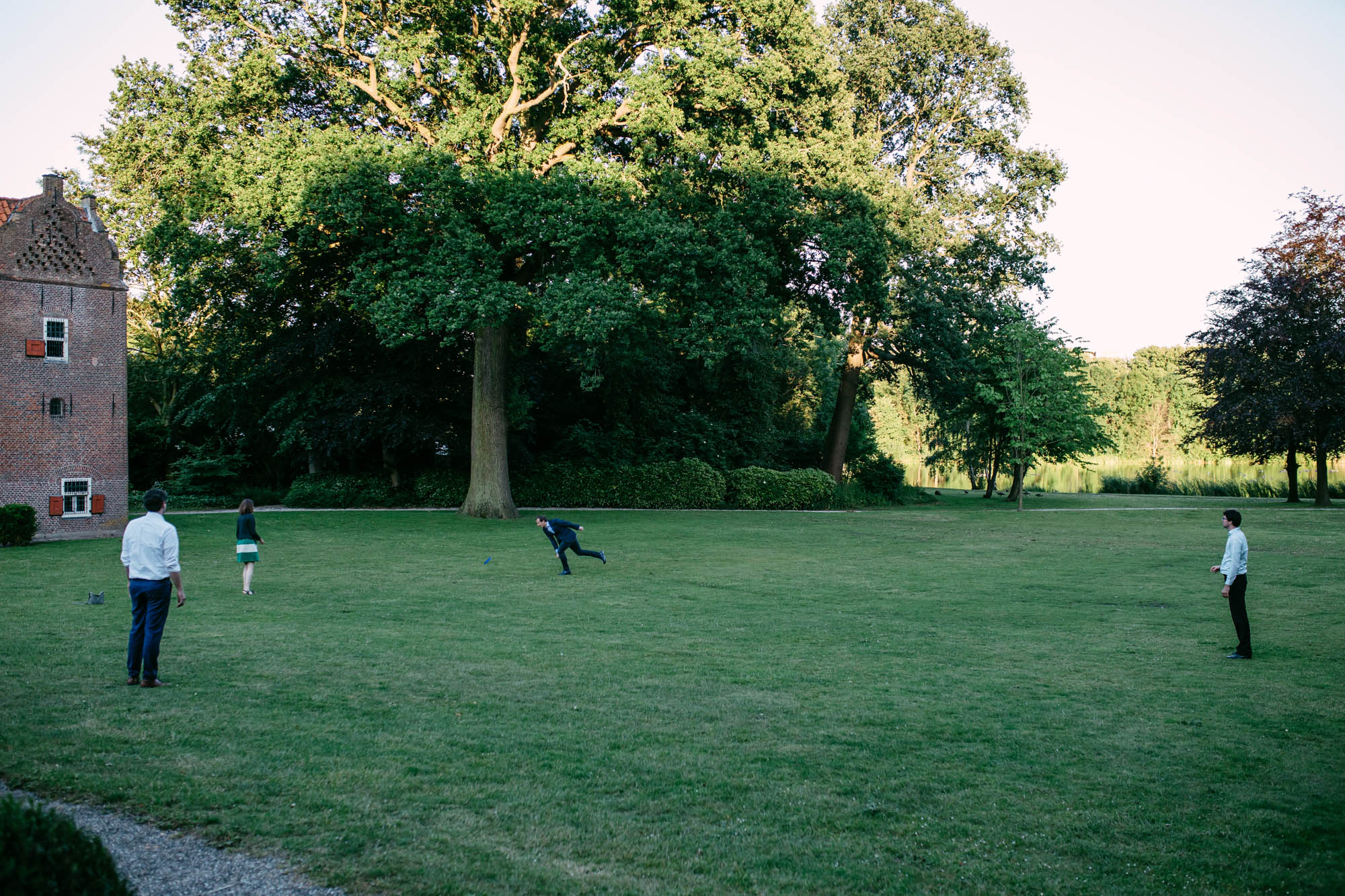 Een groep mensen die frisbee spelen in een veld tijdens een bruiloft.