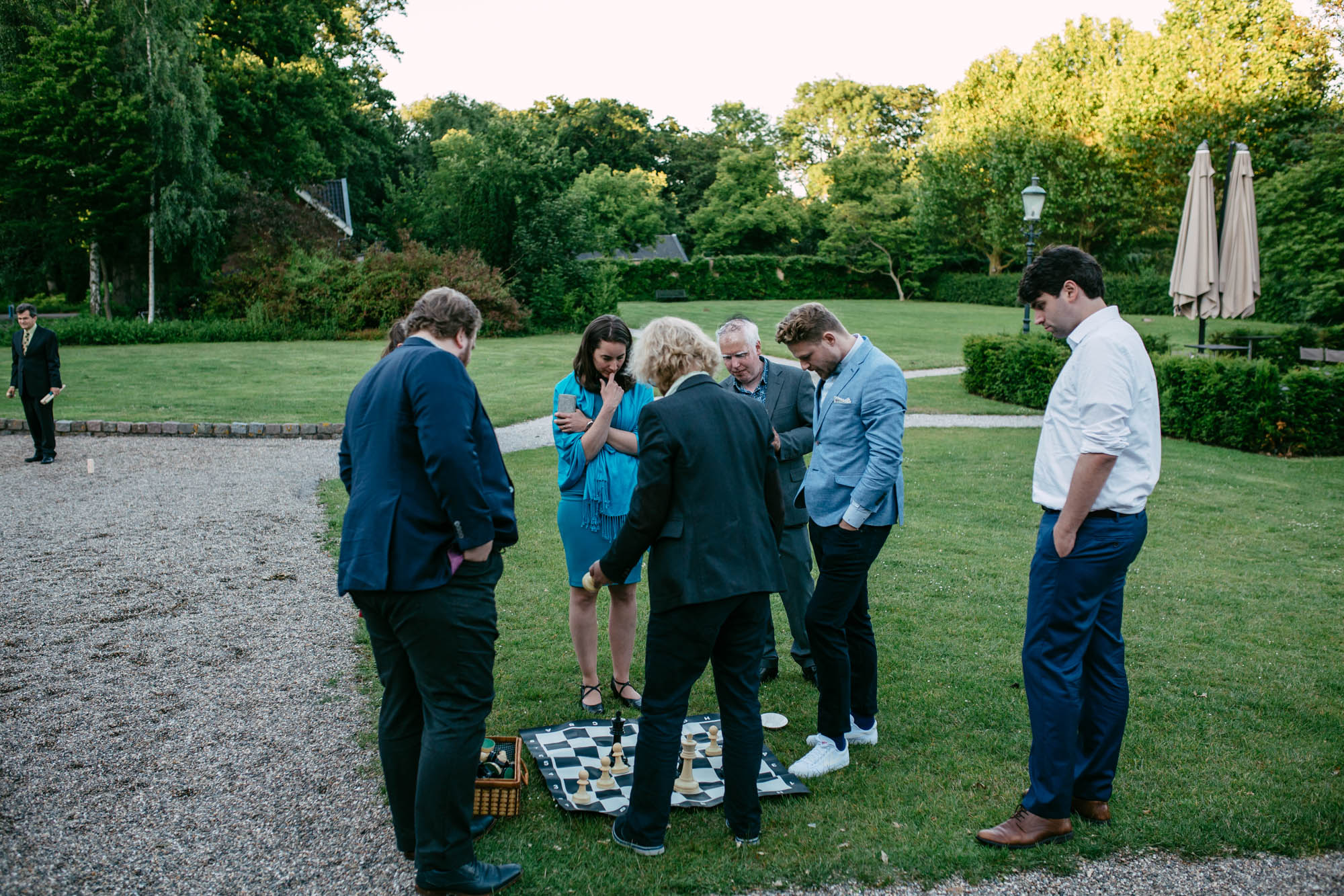 A group of people playing chess in a garden while enjoying a friendly game during a wedding celebration.