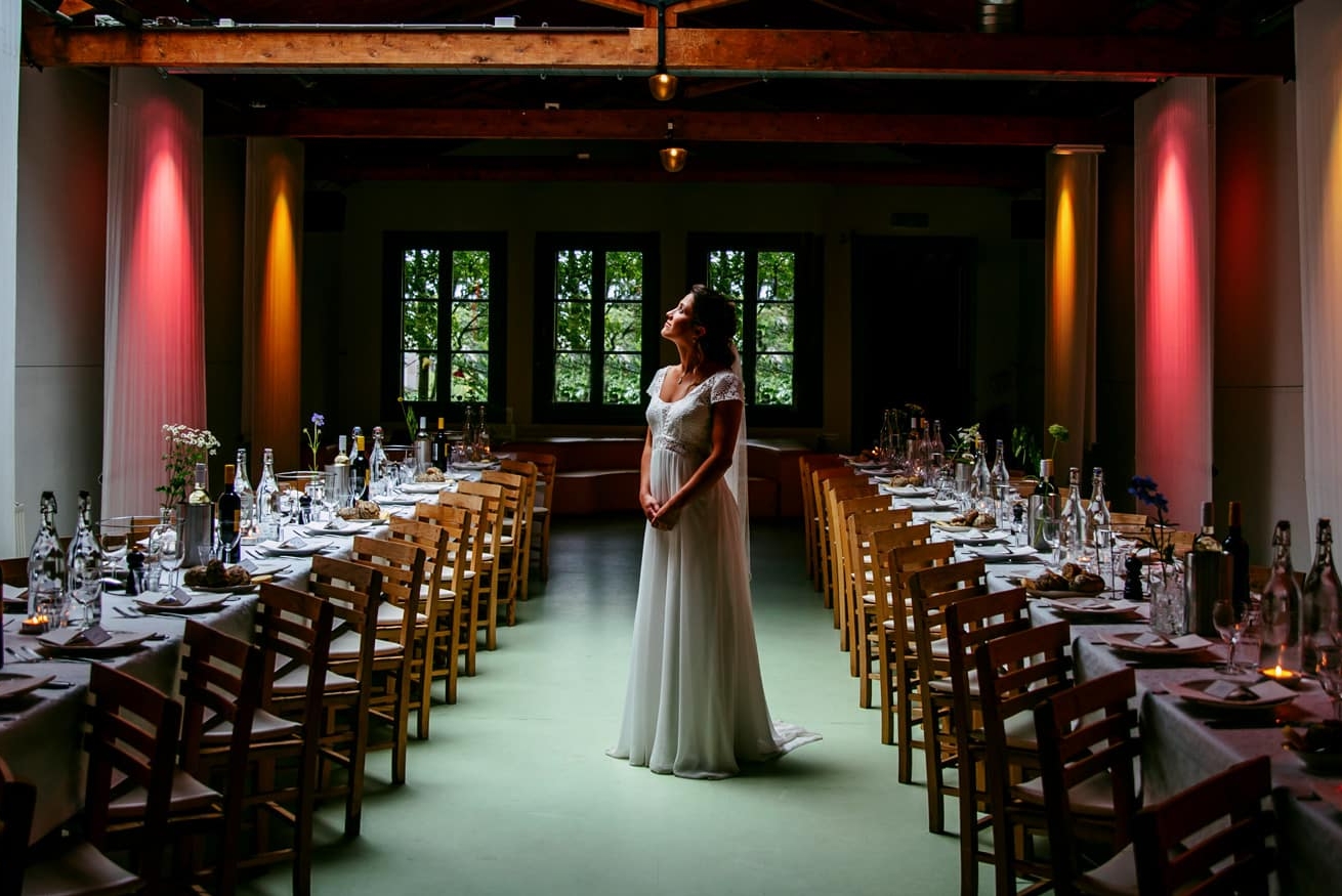A wedding dress bride standing in front of a long table.