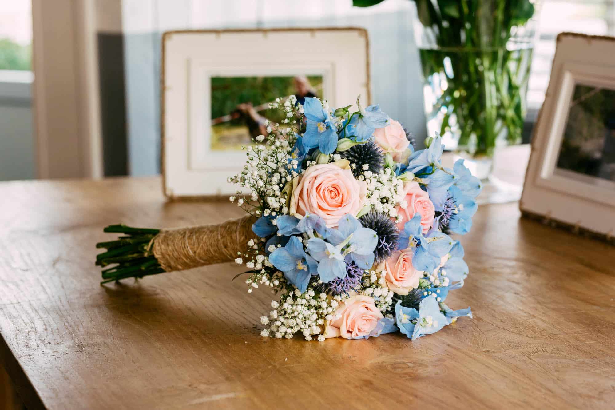 On a wooden table is a wedding bouquet of blue and pink flowers.