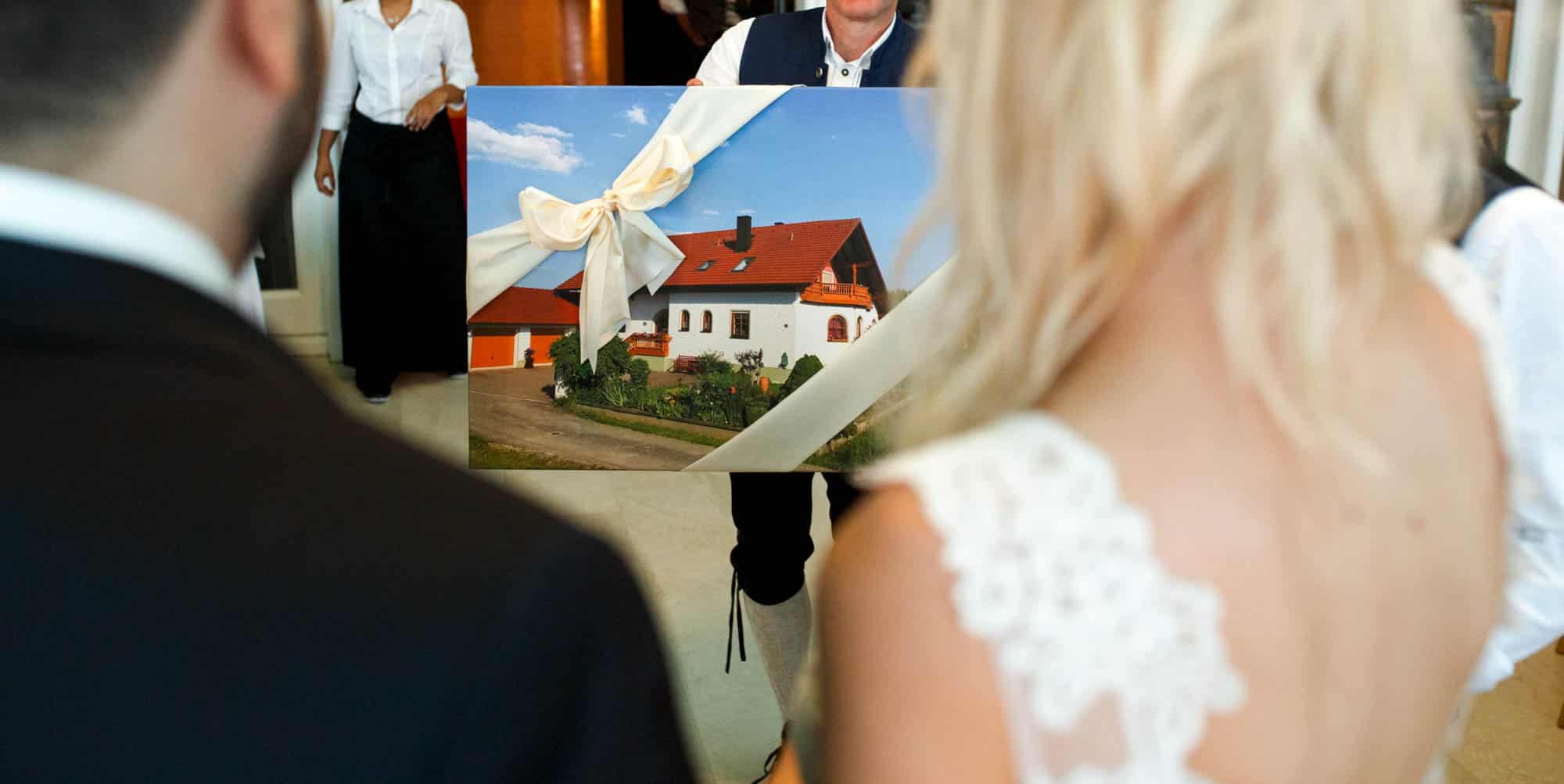 Bruid en bruidegom ontvangen een trouwdagcadeau - kijken naar een foto van een huis.
