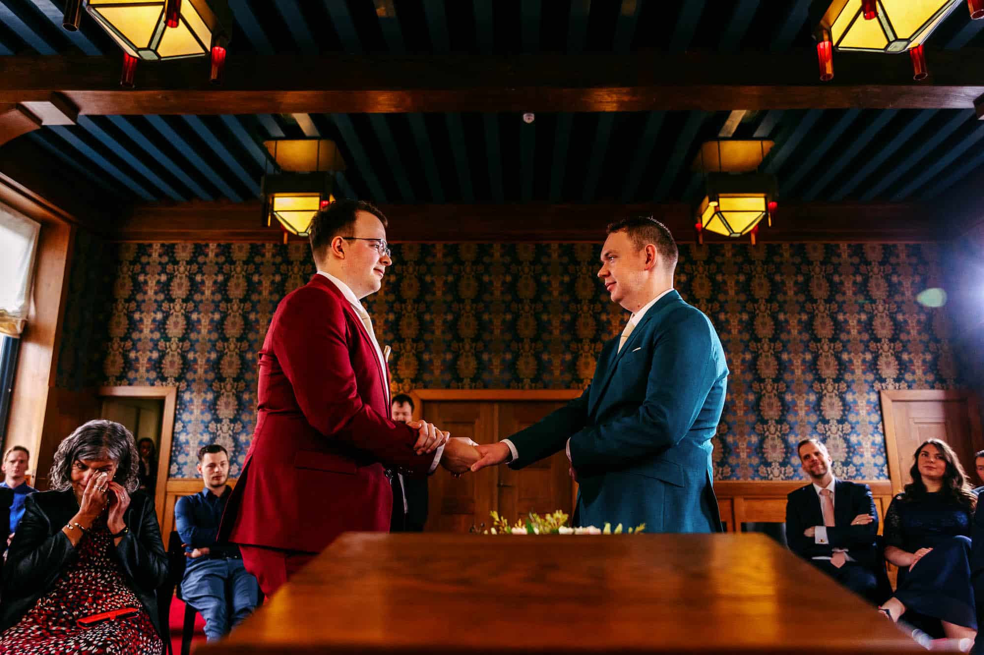 Two men shake hands during a wedding ceremony and celebrate the history of marriage.