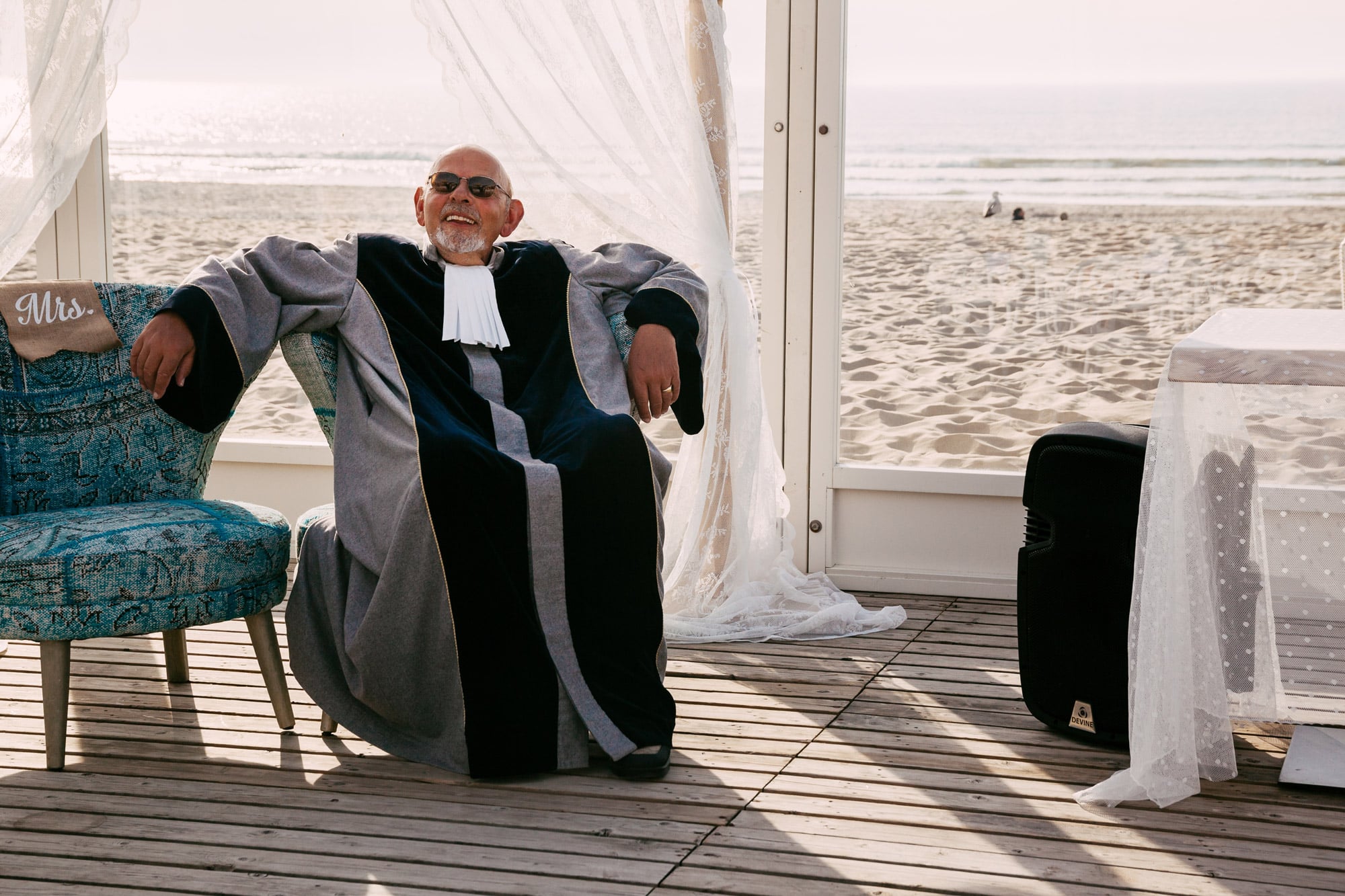    Een man in een badjas zittend op een stoel op het strand, genietend van de vredige sfeer en nadenkend over de schoonheid van de natuur.