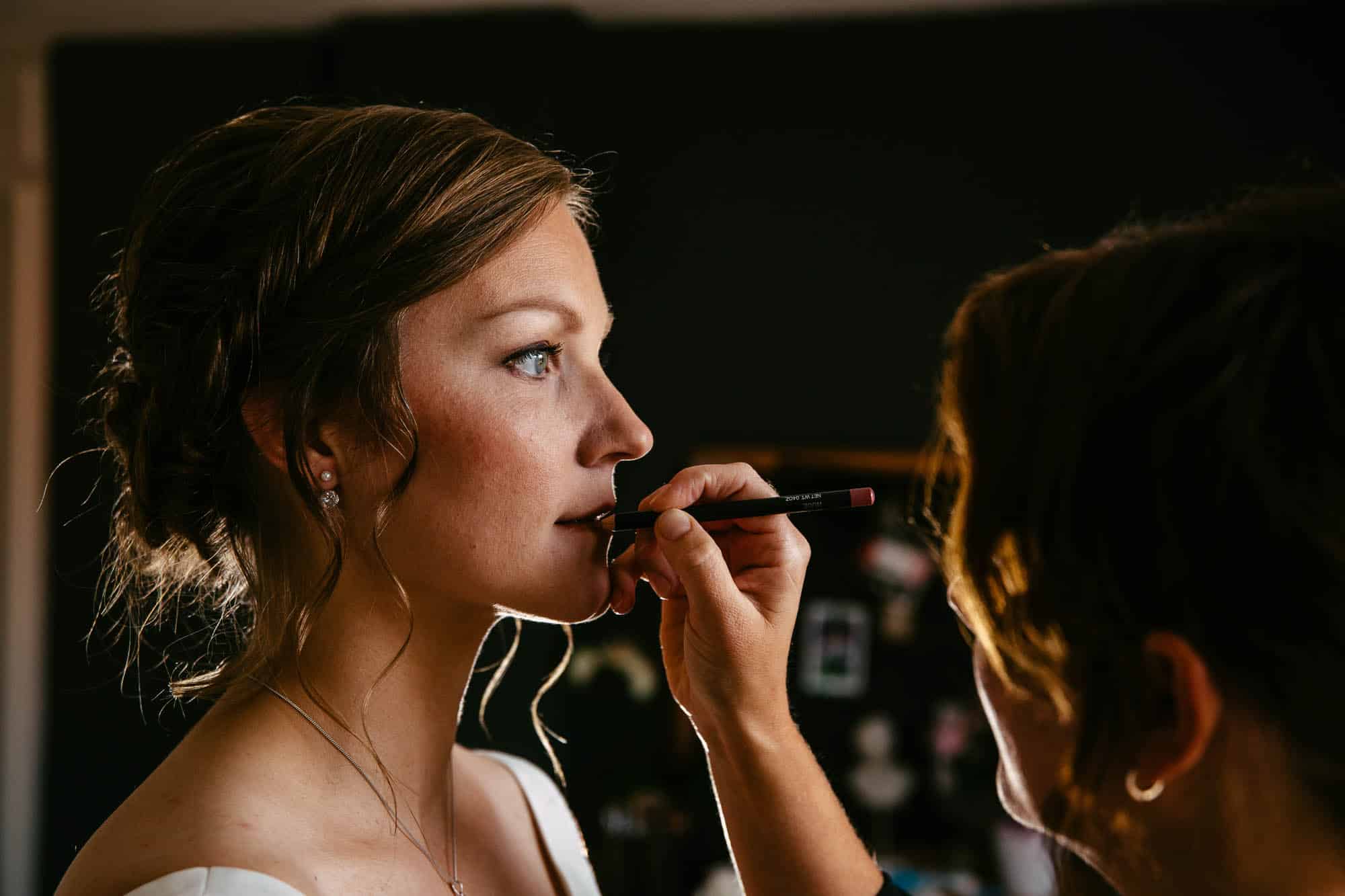 A bride having her bridal make-up done by a make-up artist.