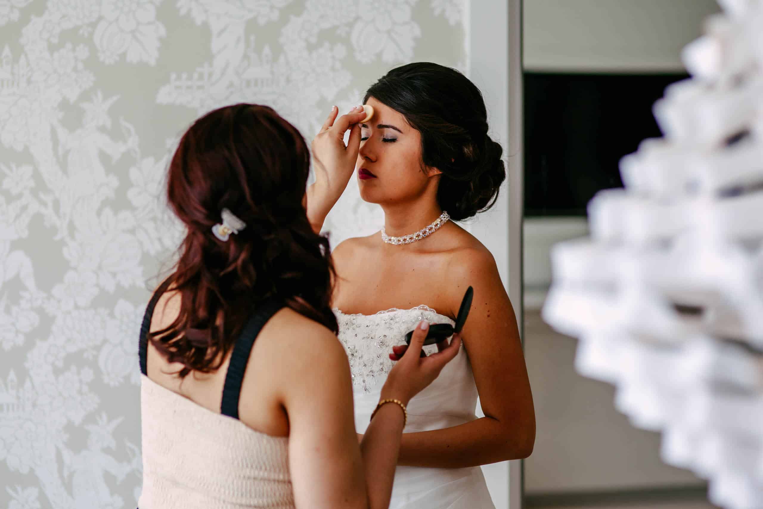 Een bruid die haar Bruidsmake-up ontvangt voor een spiegel.