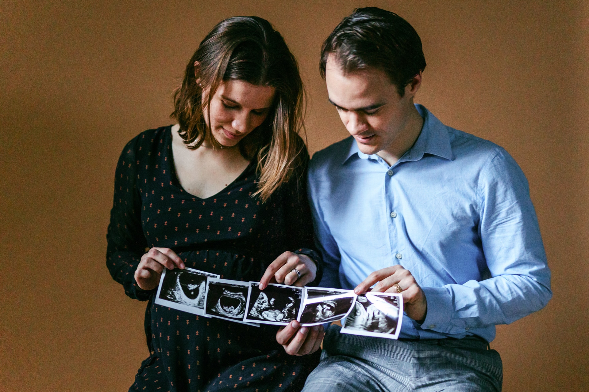 Een stel dat een Zwangerschapsshoot doet en naar een foto van een zwangere vrouw kijkt.