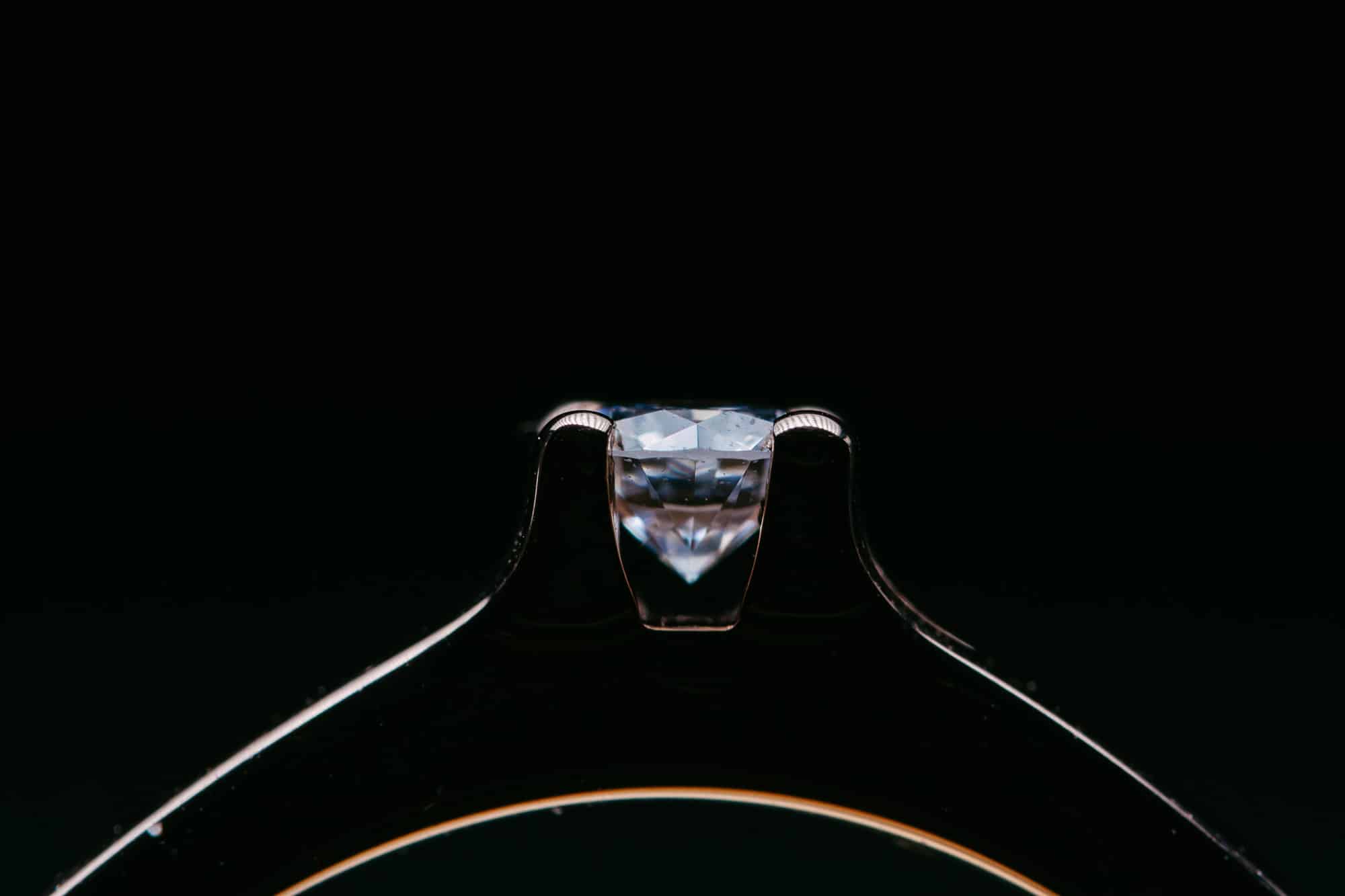 A close-up of an engaged diamond engagement ring on a black background.