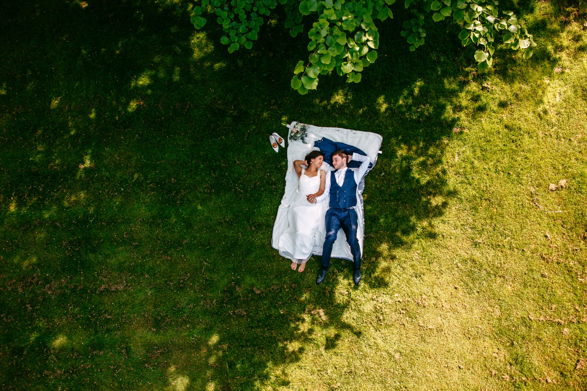 A married couple lying on the grass in the forest.
