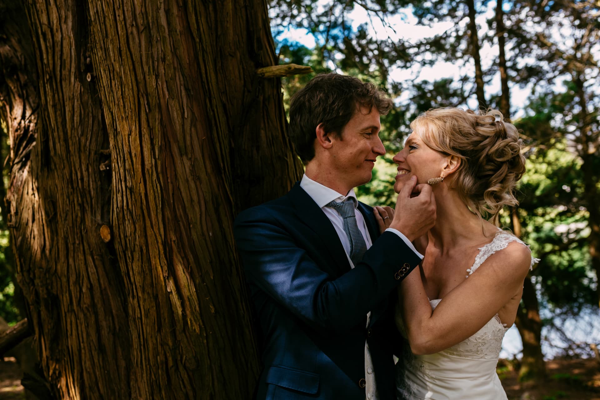 Getting married in the woods - A bride and groom hug in front of a tree.