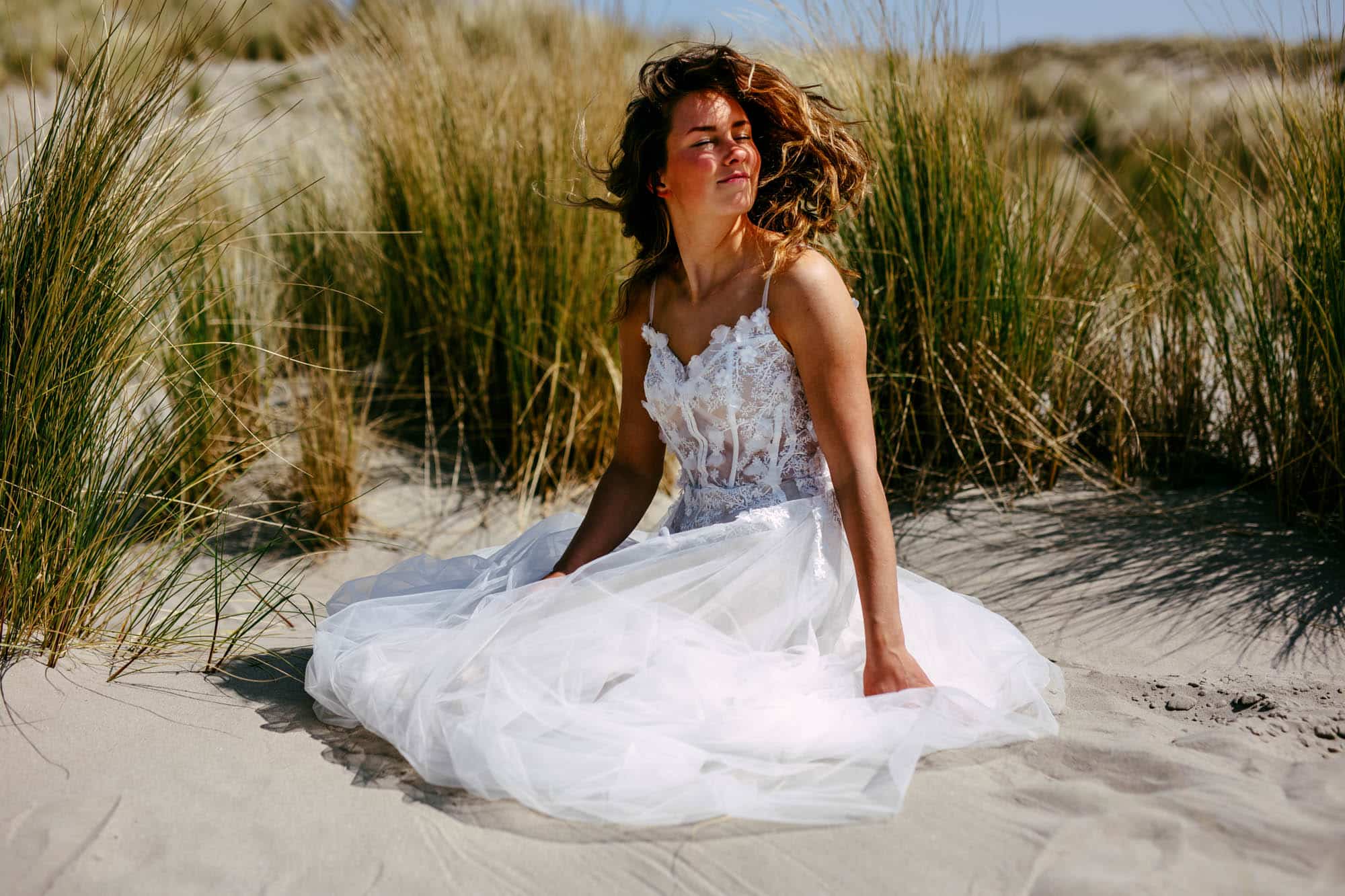 Meisje met Boho trouwjurk zittend op het strand