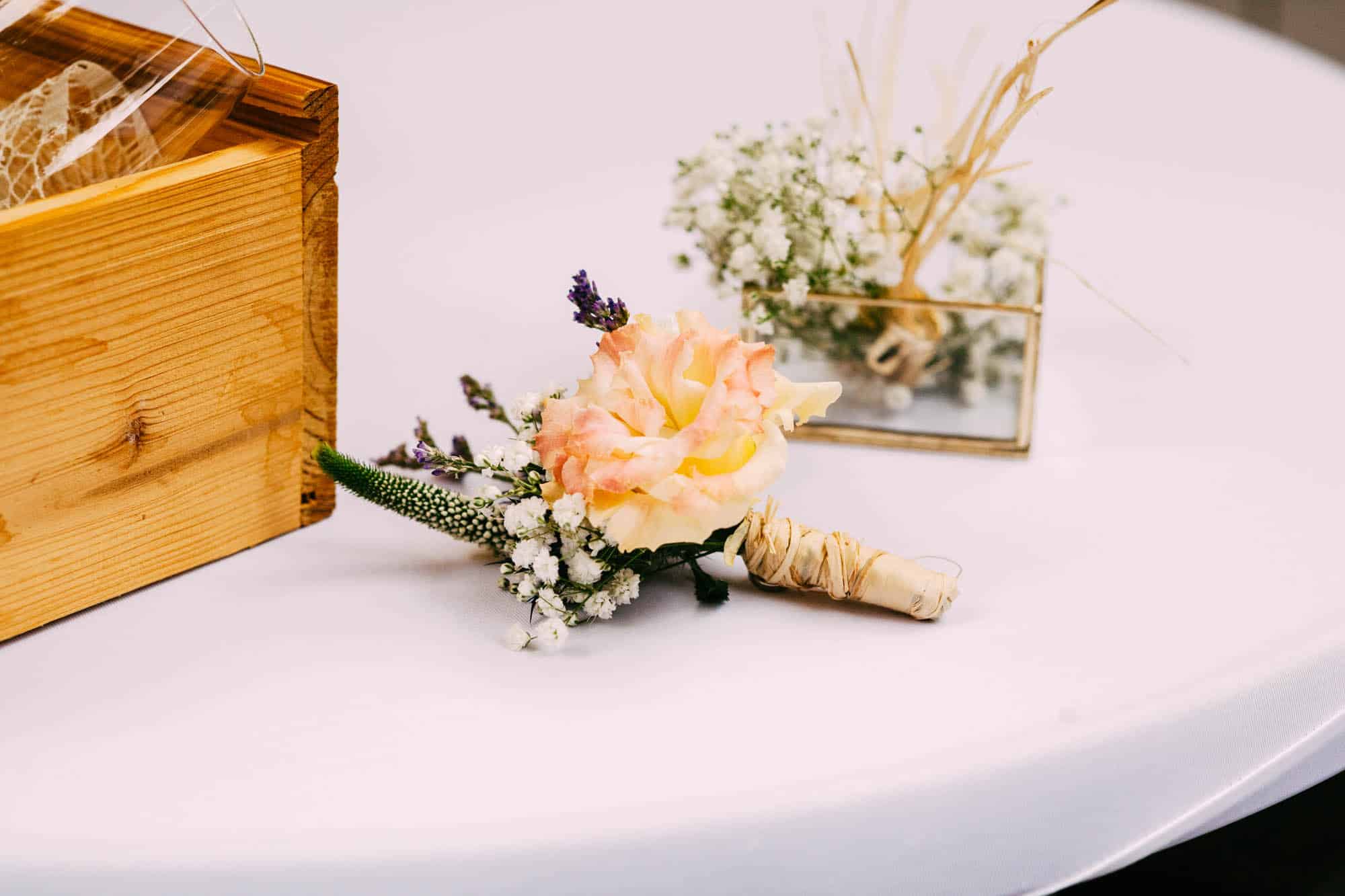 Corsage next to wedding rings and wooden box.