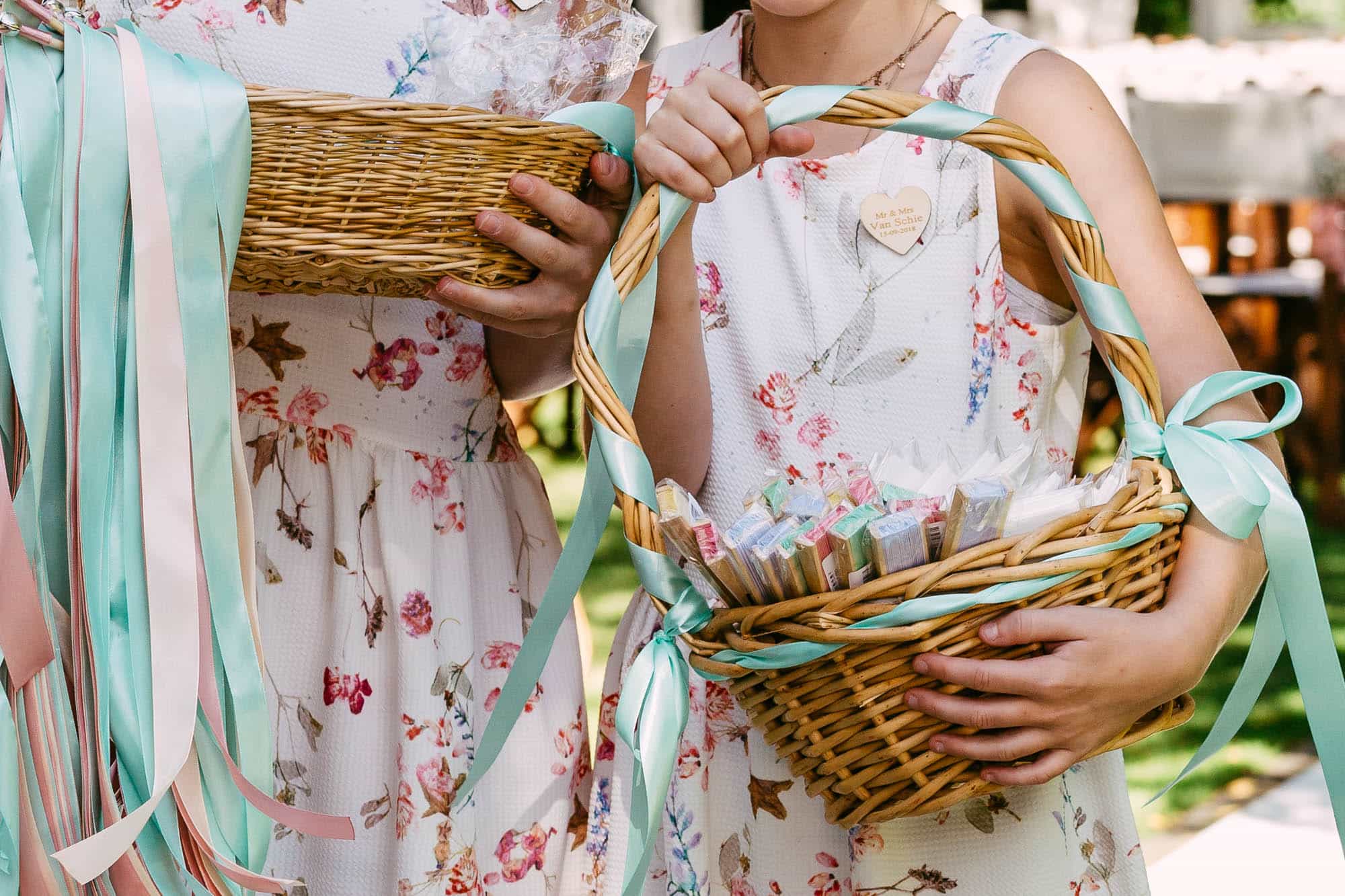 Two girls hold baskets with ribbons and corsages.