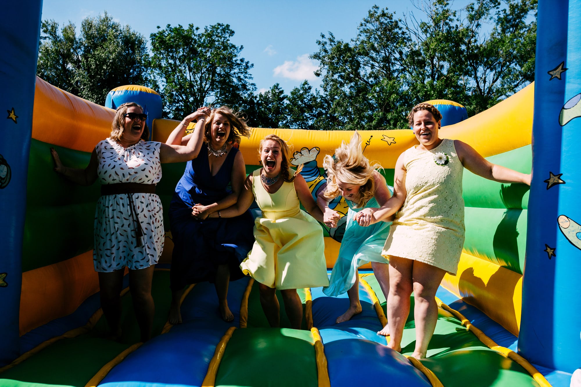 A group of casually chic women pose on a bouncy castle.
