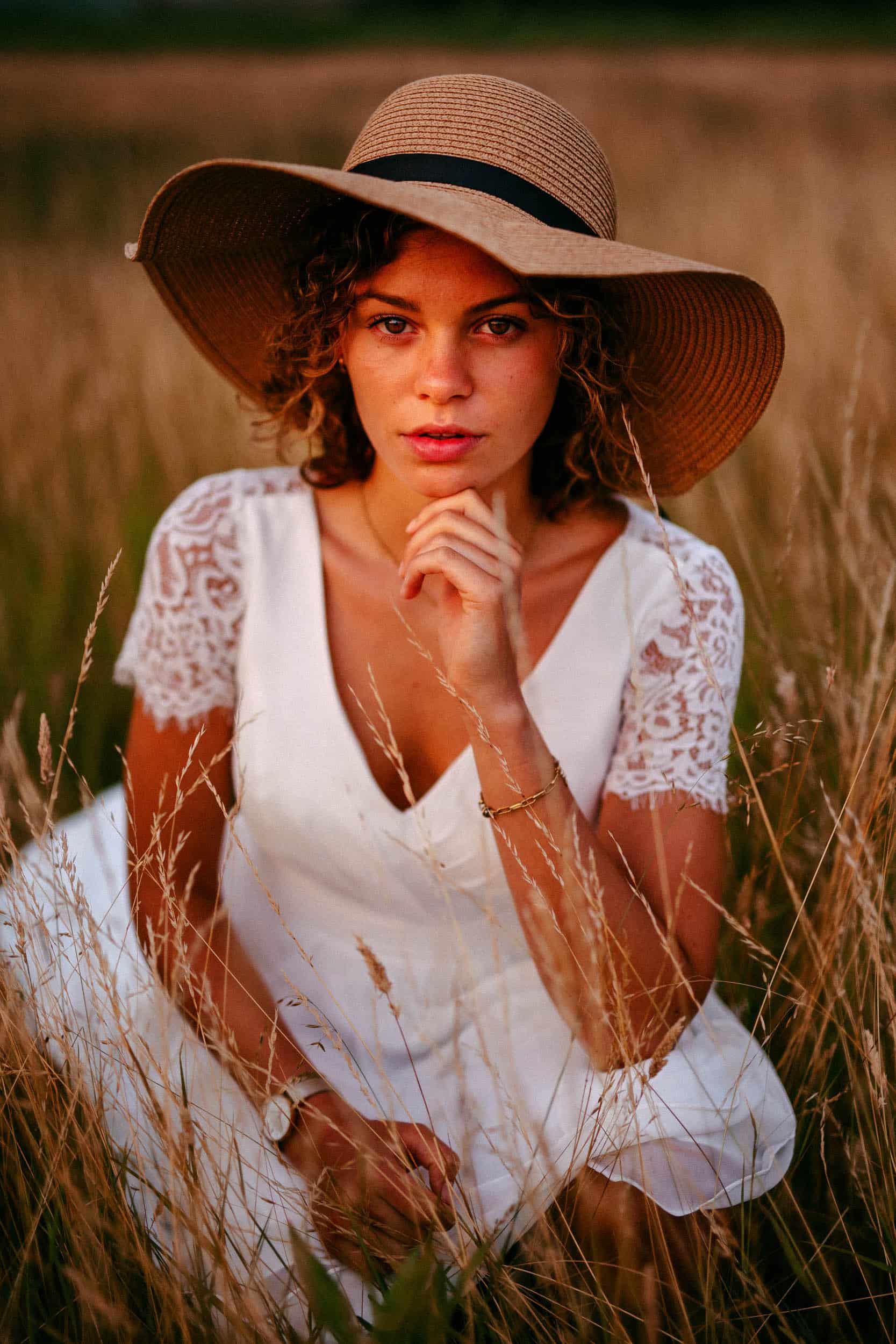 Een vrouw met een Boheemse hoed, zittend in een veld.