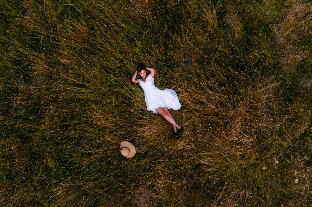 Bruid met trouwjurk liggend in het gedroogde gras