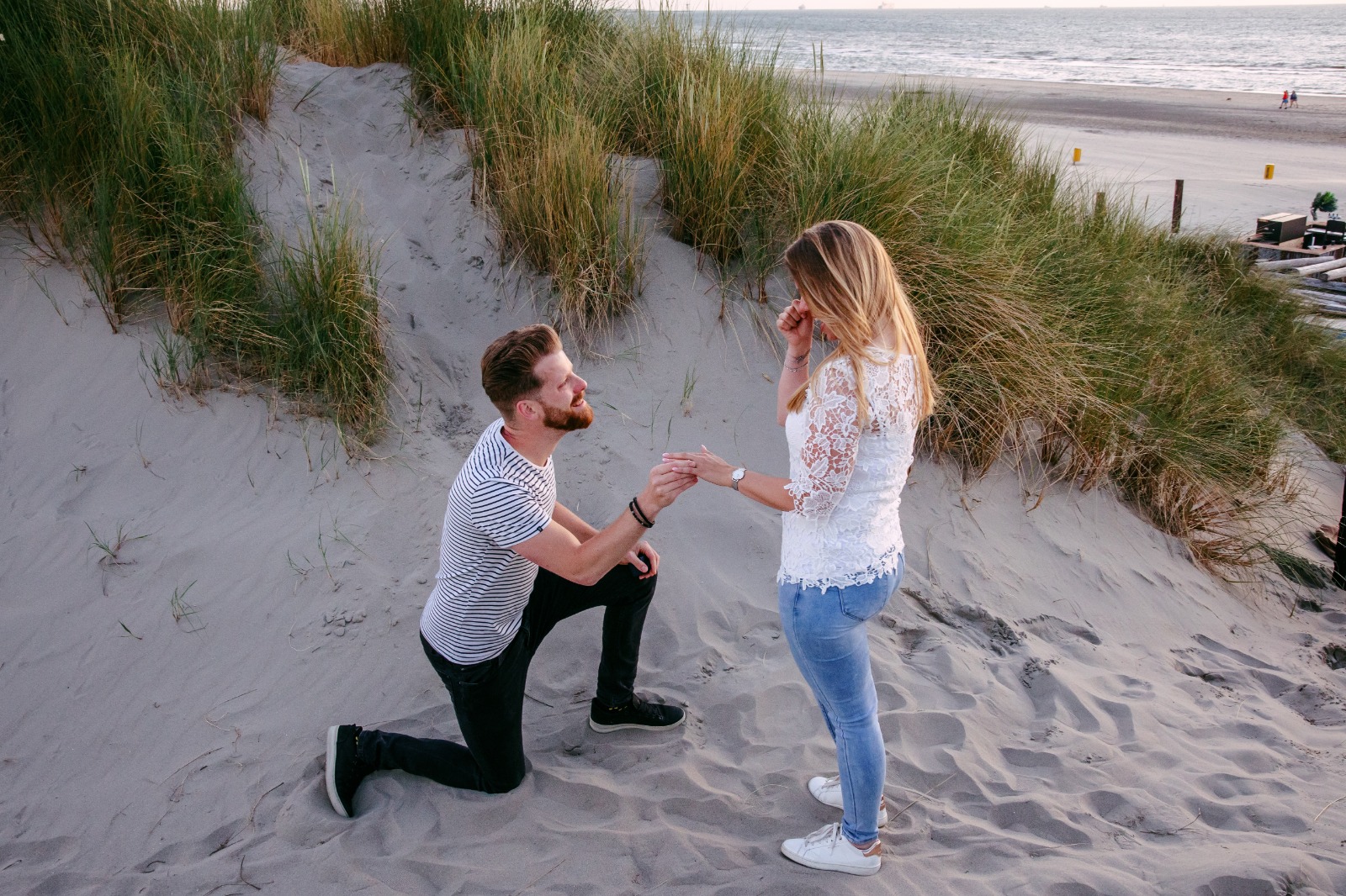 Een man maakt een romantisch huwelijksaanzoek met een vrouw op het strand.
