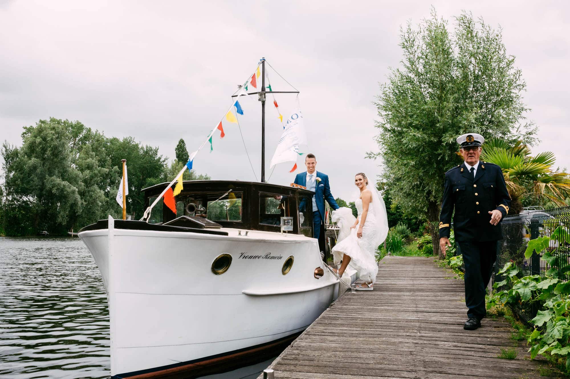 A man and woman celebrate Weddings in Rotterdam as they walk a boat on a quay.