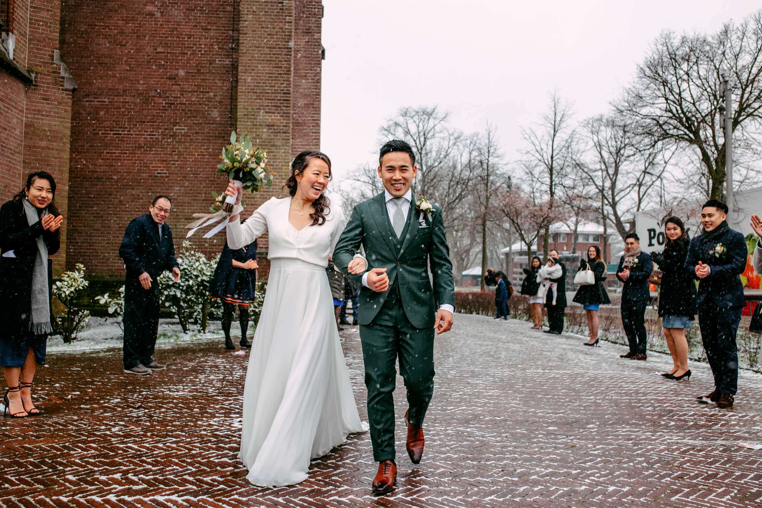 A couple walking across a stone walkway in the snow, with a wedding theme.