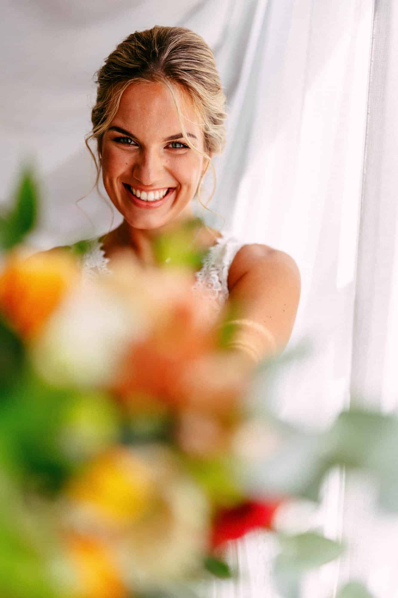 A bride smiles while holding a bouquet of flowers during her bridal shower.