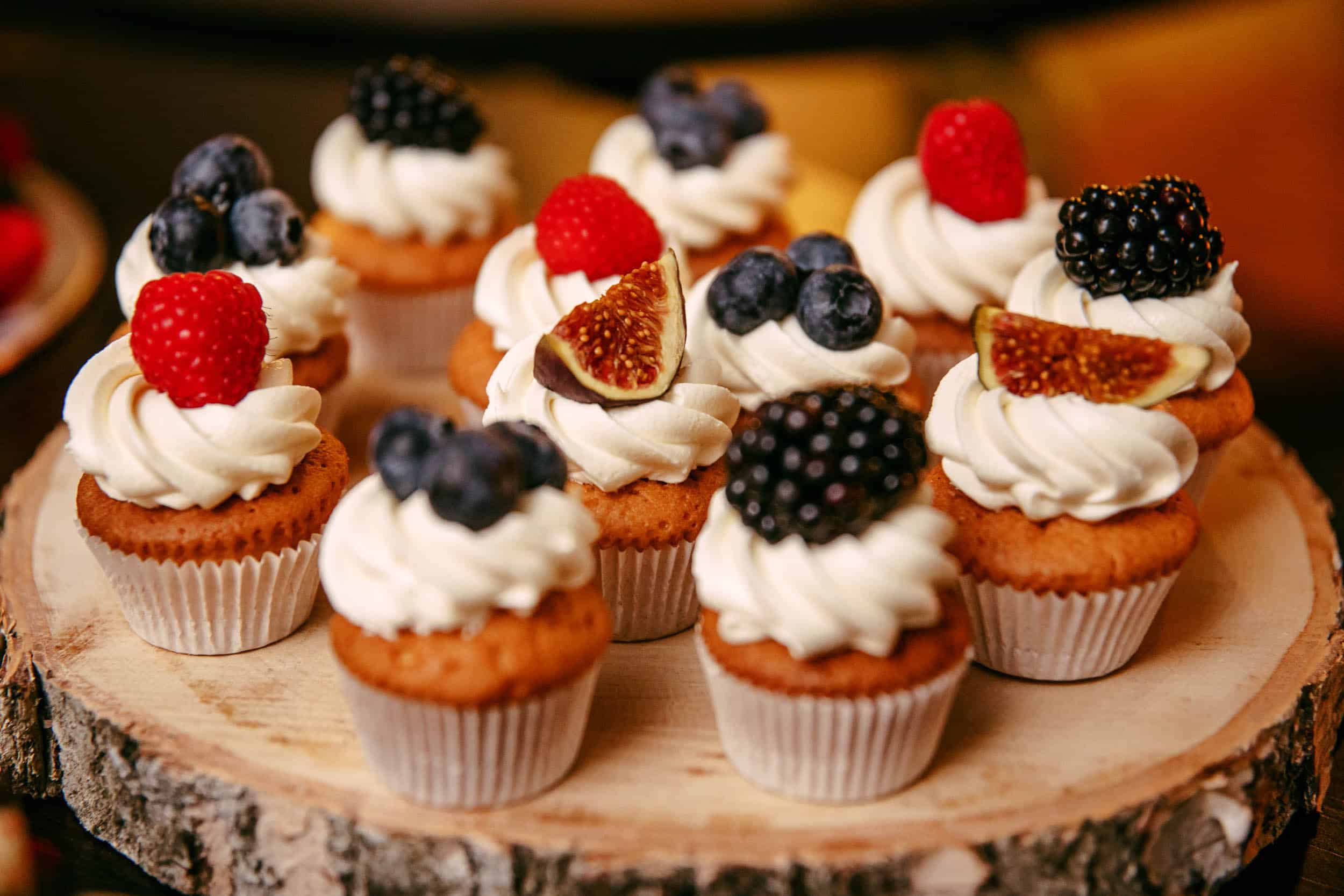 Cupcakes garnished with berries and whipped cream, perfect for a wedding theme.