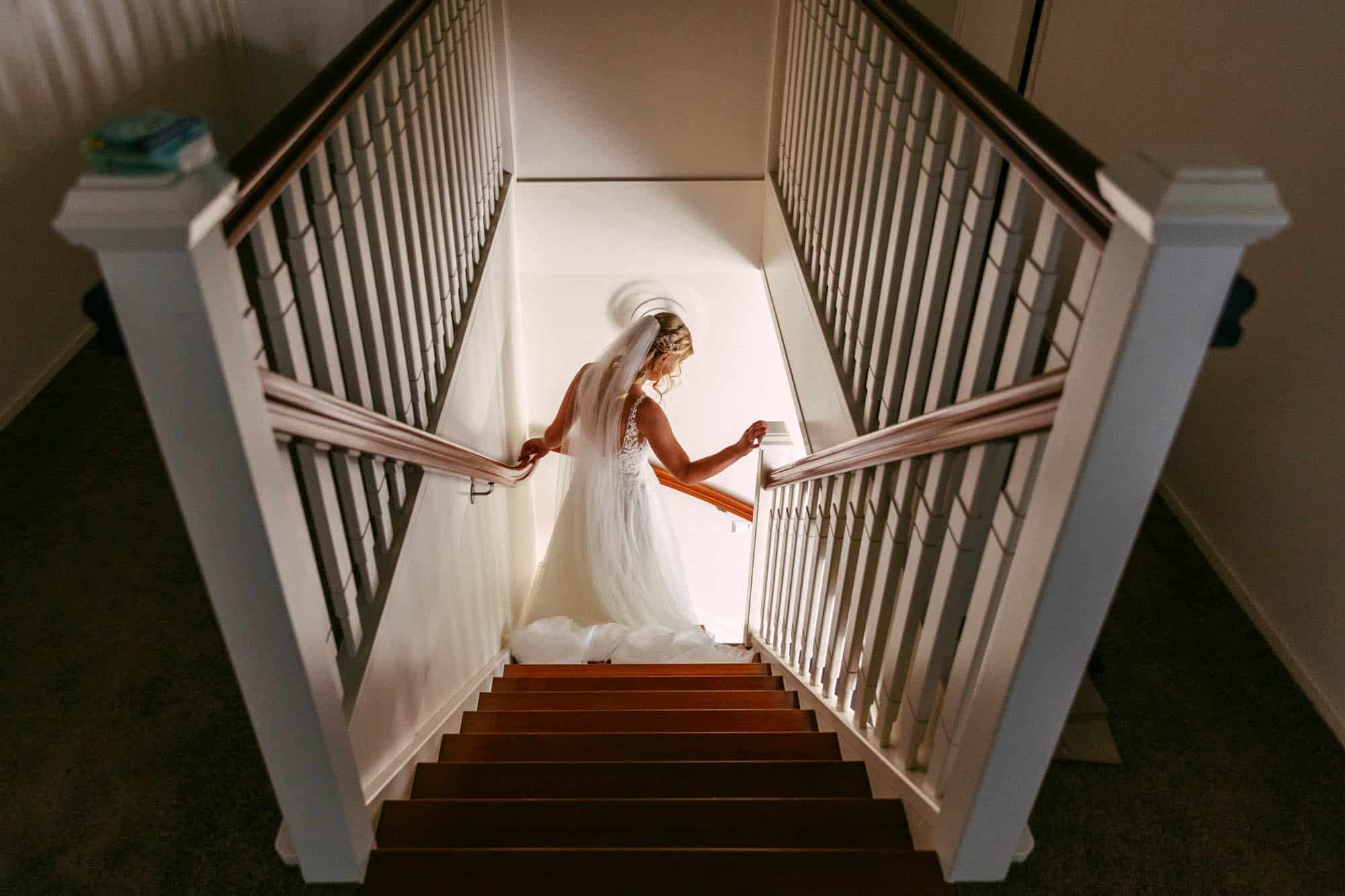Een bruid daalt sierlijk de trap af in haar trouwjurk tijdens ondertrouw.