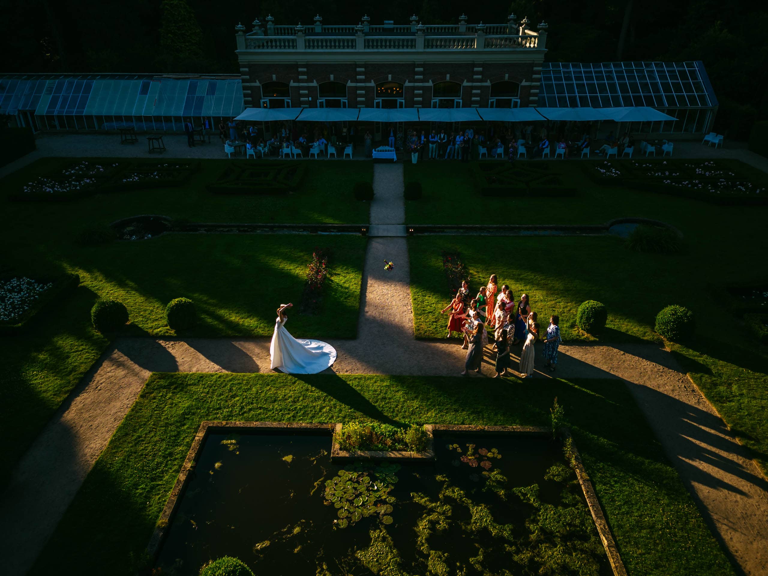 Een bruid en bruidegom die over een pad in een tuin lopen en de essentie van bijzondere trouwfoto's vastleggen.