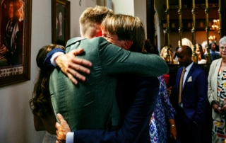 Trouwfoto's van een man die een andere man knuffelt in een kerk.