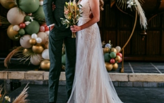 Trouwfotos: Een bruid en bruidegom die een kus delen omringd door ballonnen in een kerk.