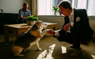 Een man aait een hond in een woonkamer terwijl hij Trouwfoto's maakt.
