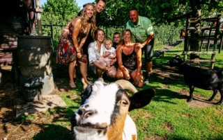 Een groep mensen poseert voor een foto met een geit tijdens bijzondere trouwfoto's.