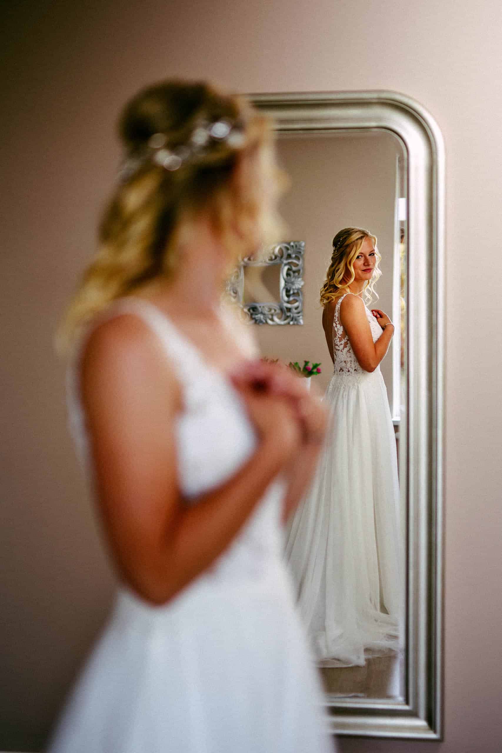 A bride in wedding dress looking at herself in the mirror while referring to her wedding checklist.
