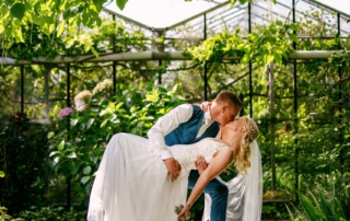 Een koppel deelt een romantische kus onder een boom in een charmante tuin als onderdeel van hun trouwdag.