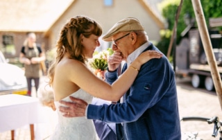 Een bruid omhelst haar grootvader op een Trouwfotos.