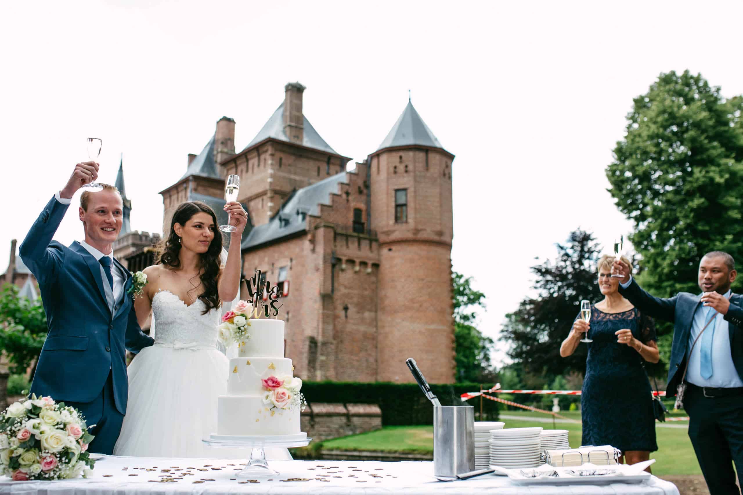 A bride and groom cut their wedding cake in front of a castle, one of the most enchanting wedding venues in South Holland.